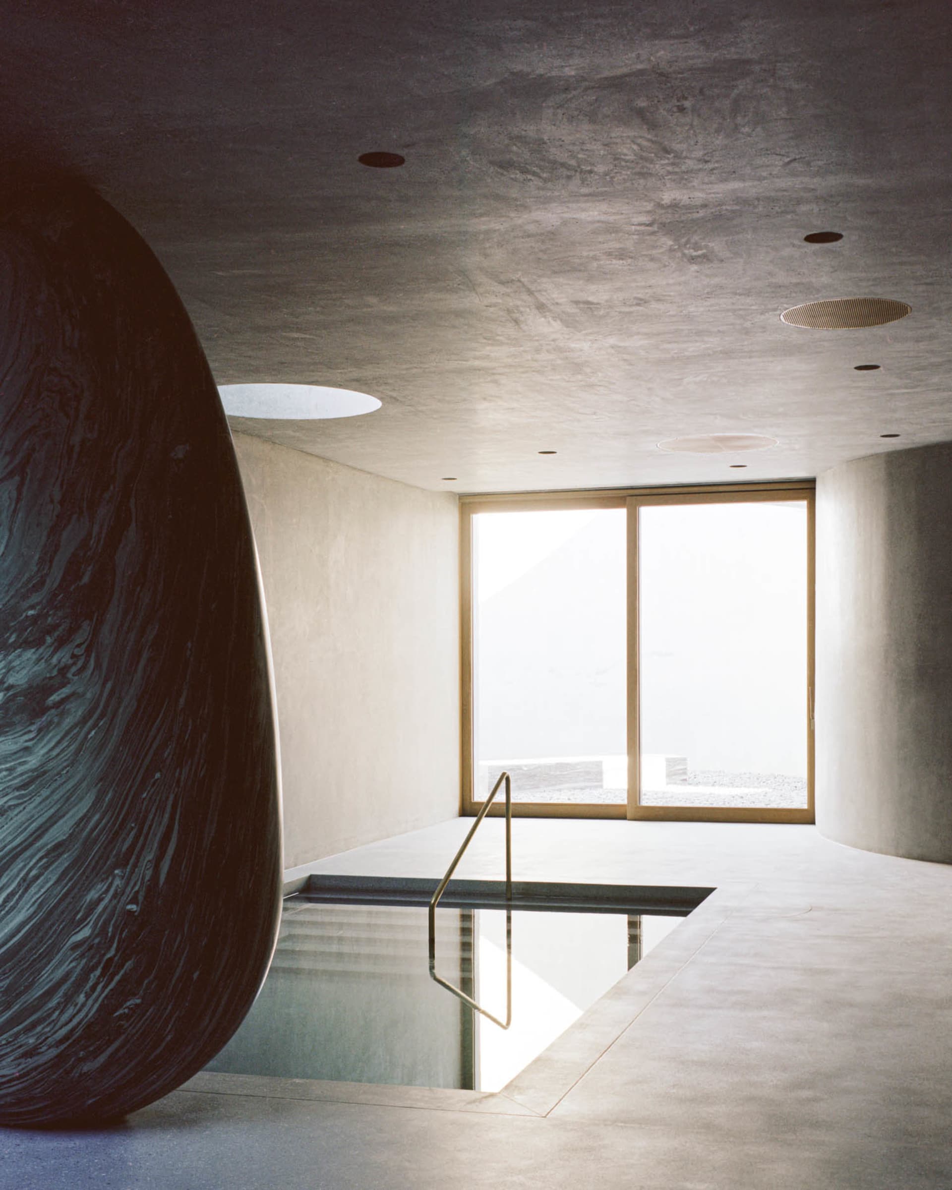 A minimalist swimming pool interior made of concrete, featuring sleek lines and a modern design.