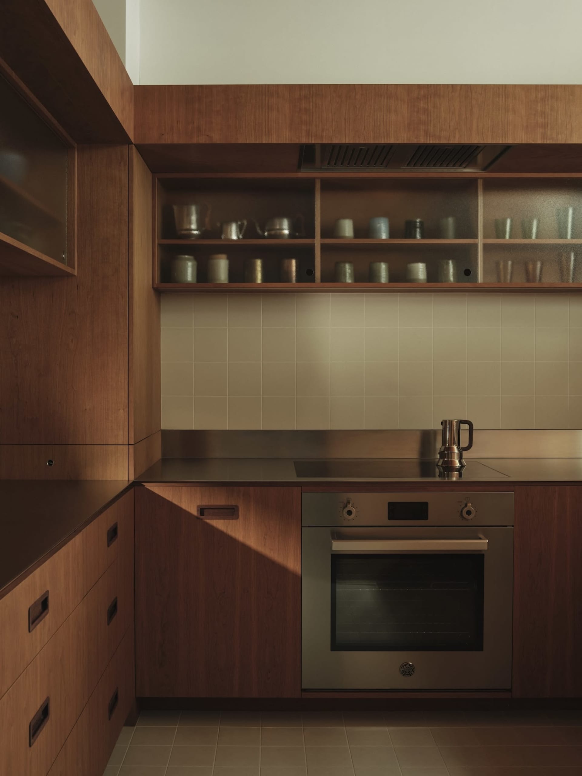 Modern kitchen with wooden cabinets and glass countertops, featuring a built-in stove and oven.