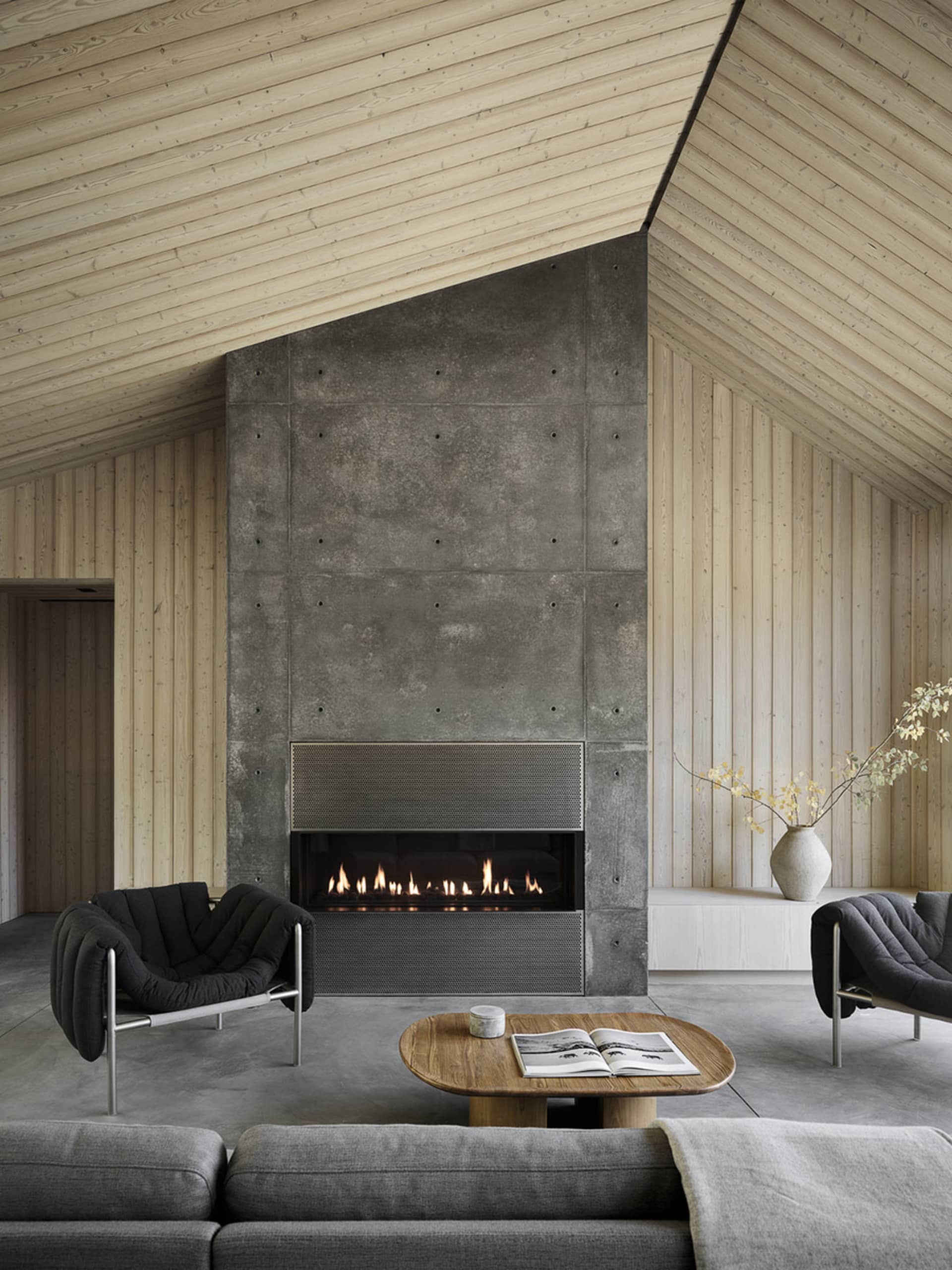 A modern living room featuring a concrete fireplace and wooden walls and ceiling.
