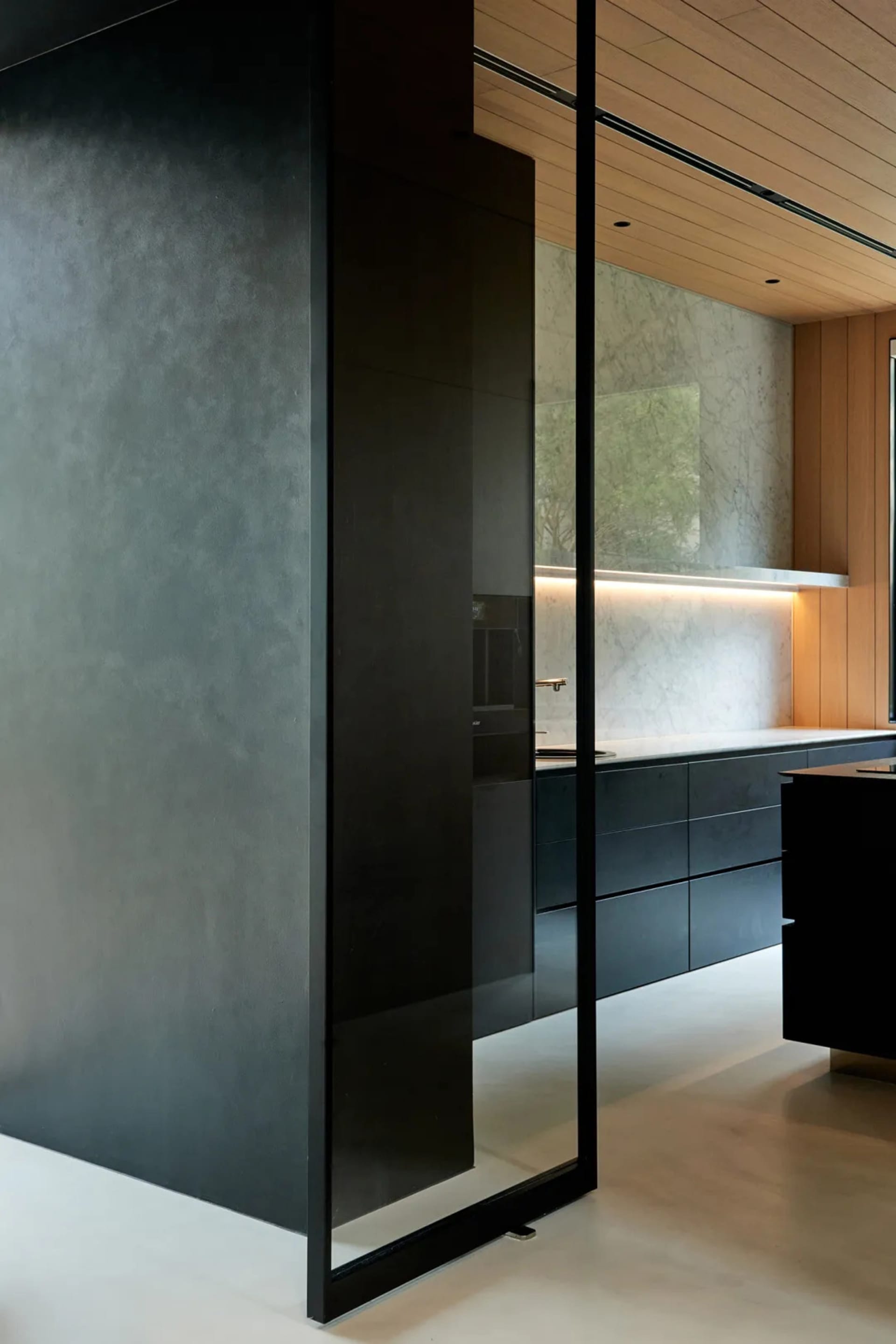 A modern kitchen with sleek concrete walls and large glass features.