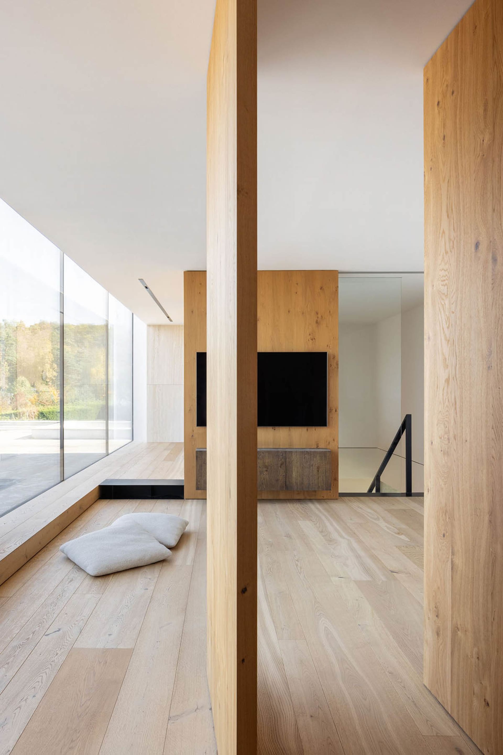 A modern minimalist living room with wooden walls and a television mounted on the wall.
