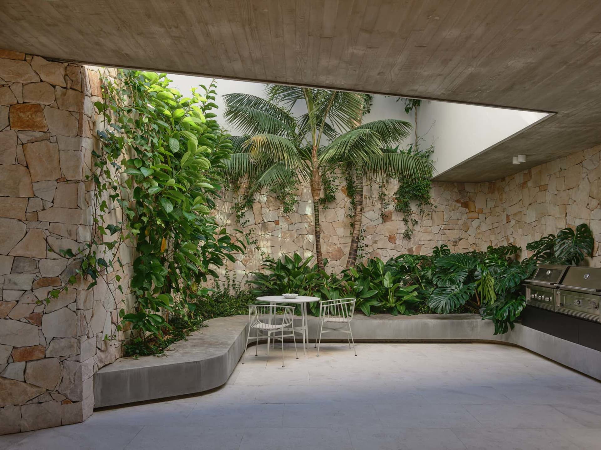 Outdoor living space featuring modern design with stone, concrete, and lush greenery.