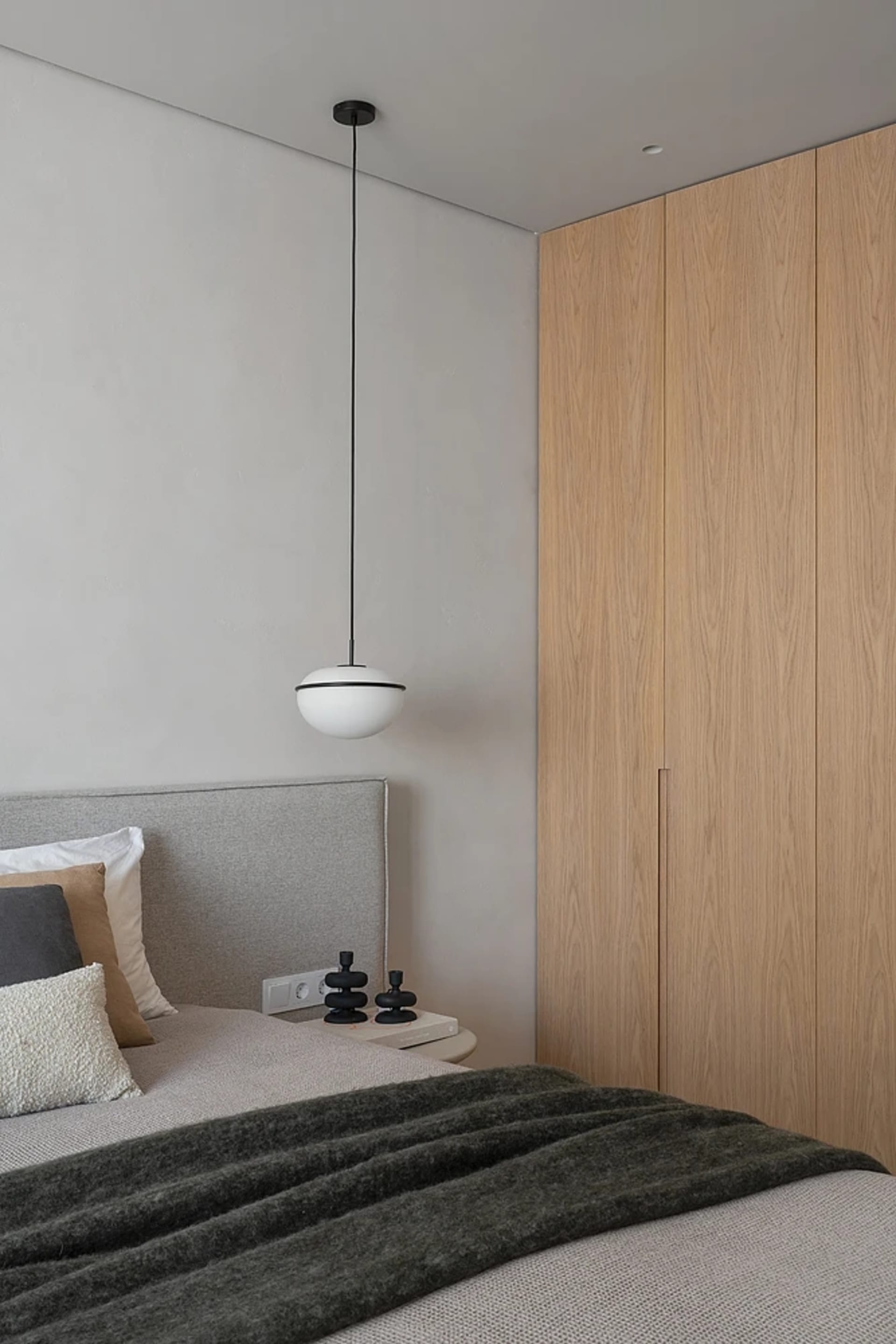 Minimalist bedroom featuring wooden features and a bed with pillows and a blanket.