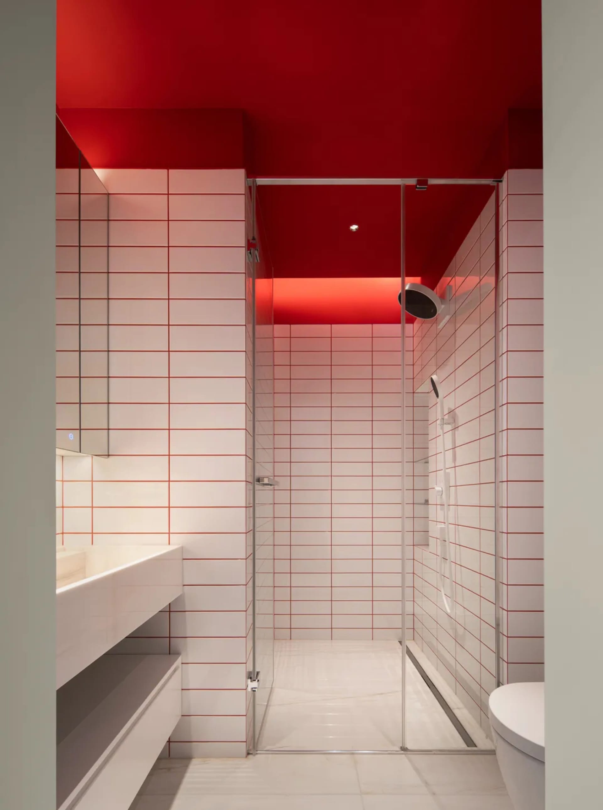 Modern bathroom with red ceiling and white tiled walls.