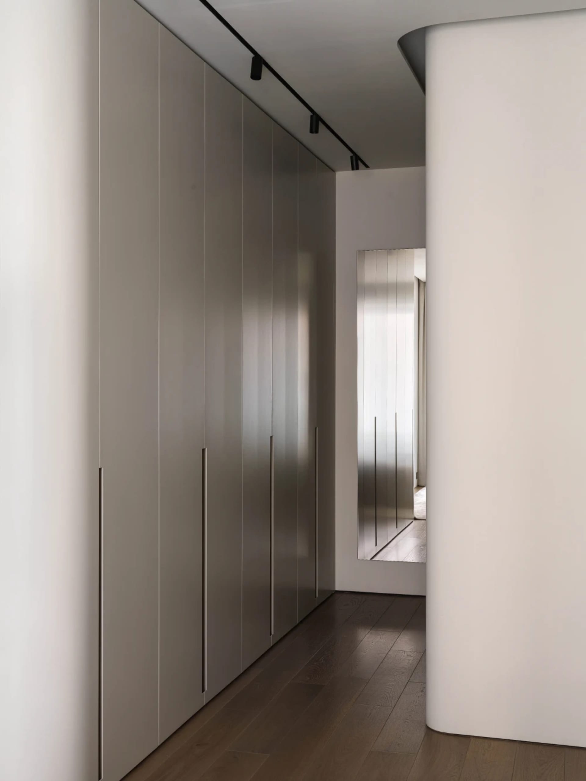 Modern minimalist bedroom with white cabinets and wooden flooring.