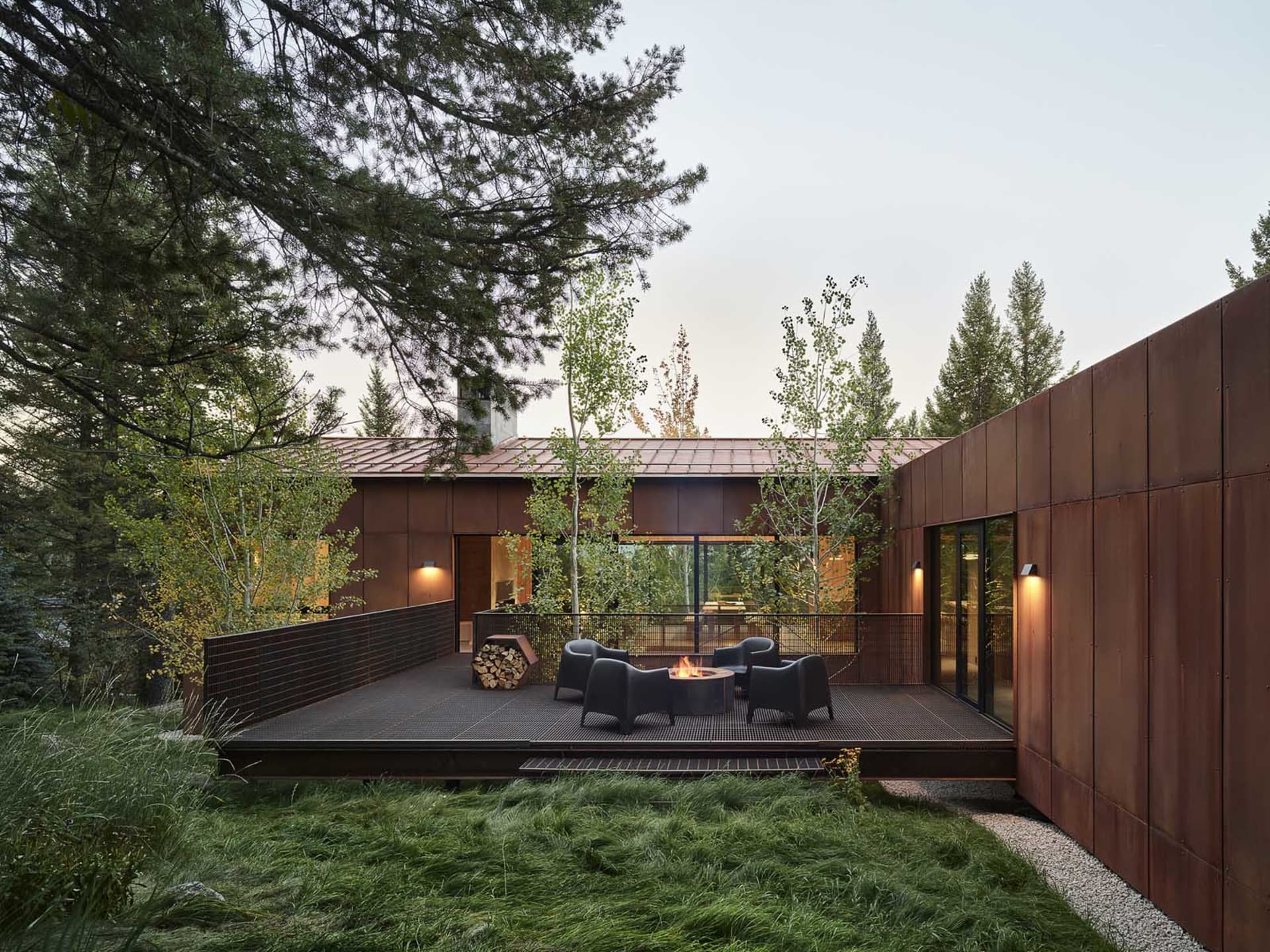 Modern industrial residential exterior with metal siding and a fire pit on the patio.