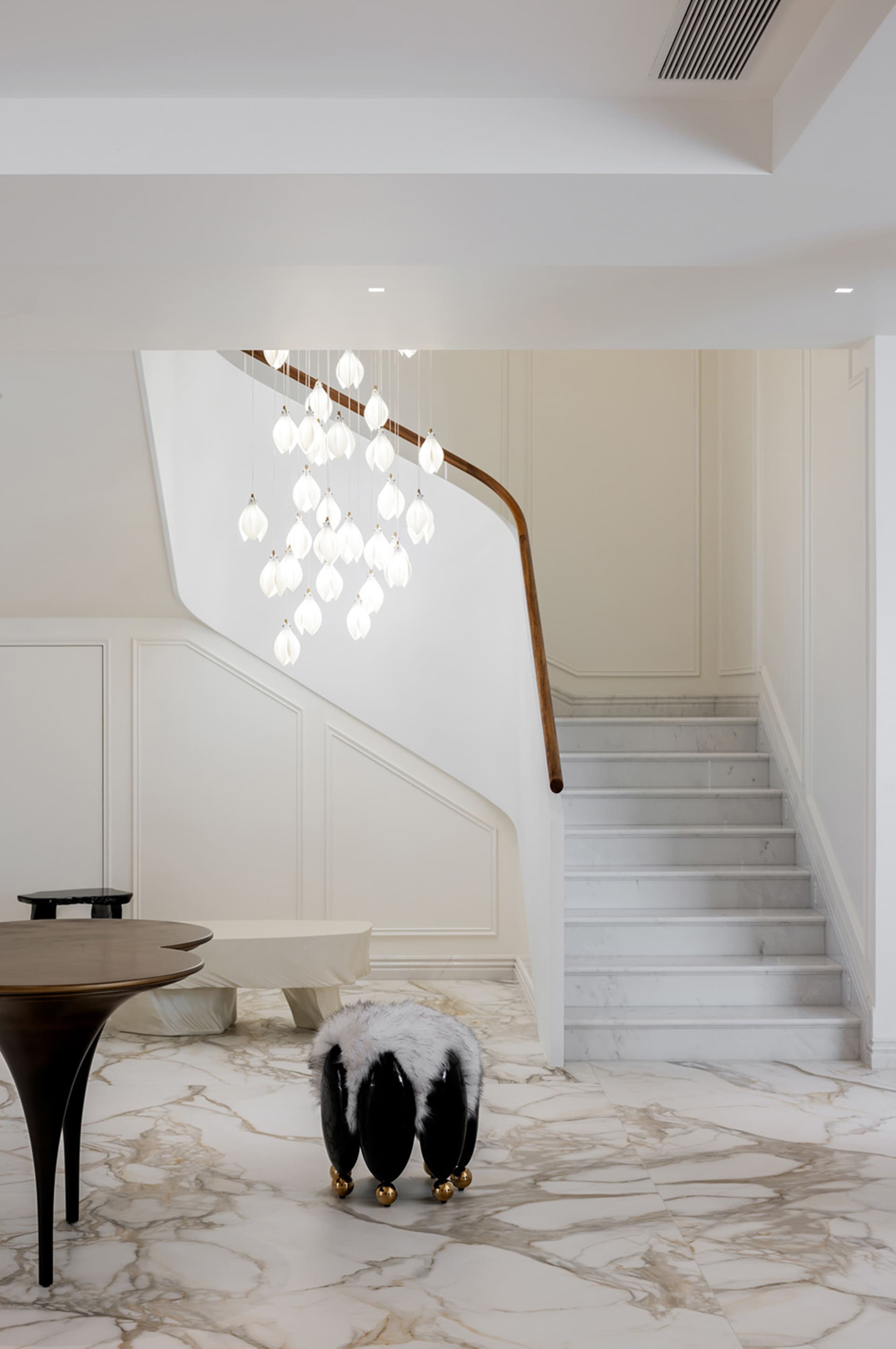 A modern interior space featuring a grand staircase with marble steps and a white marbled floor.