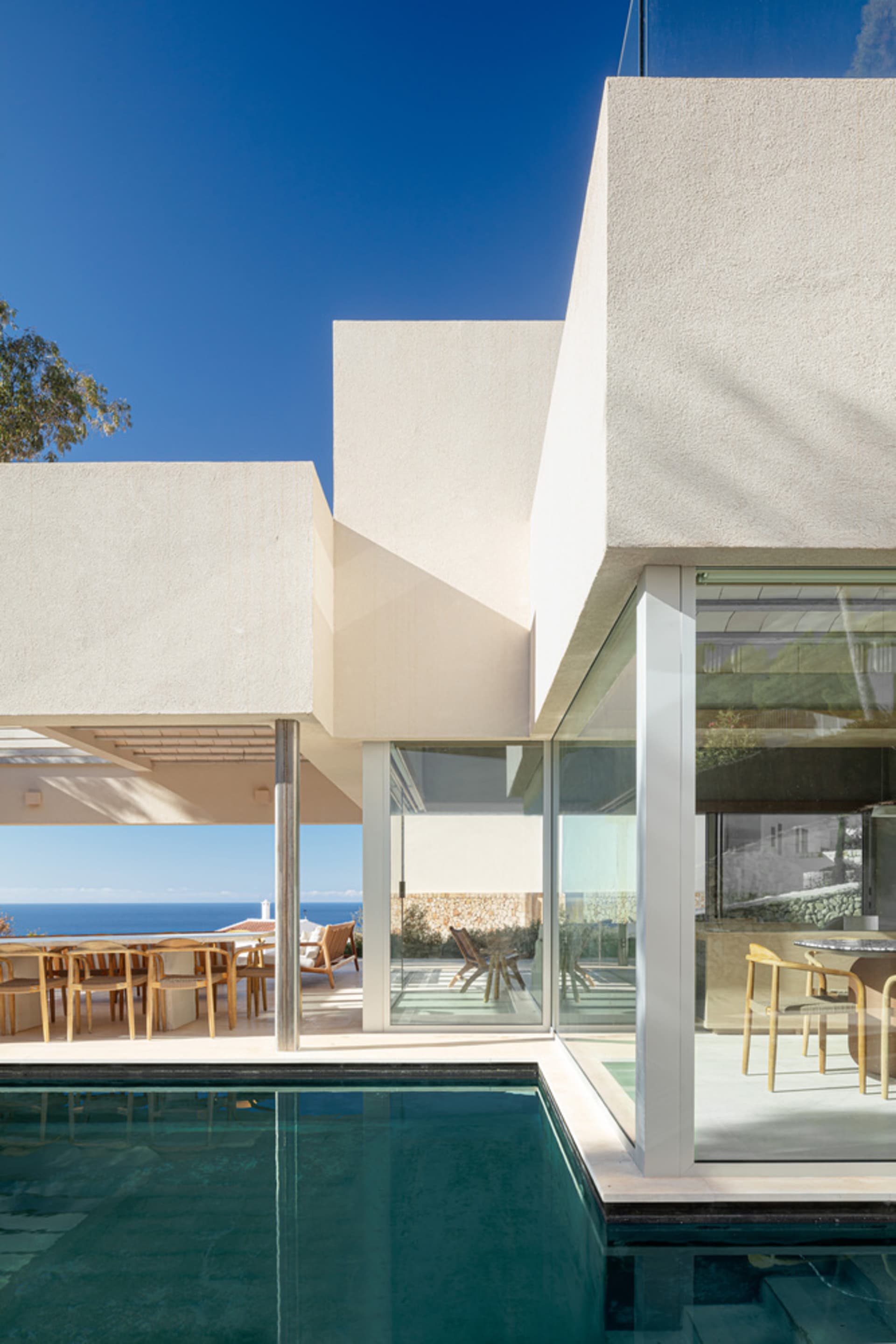 Modern residential home with concrete exterior, glass walls, and a swimming pool.