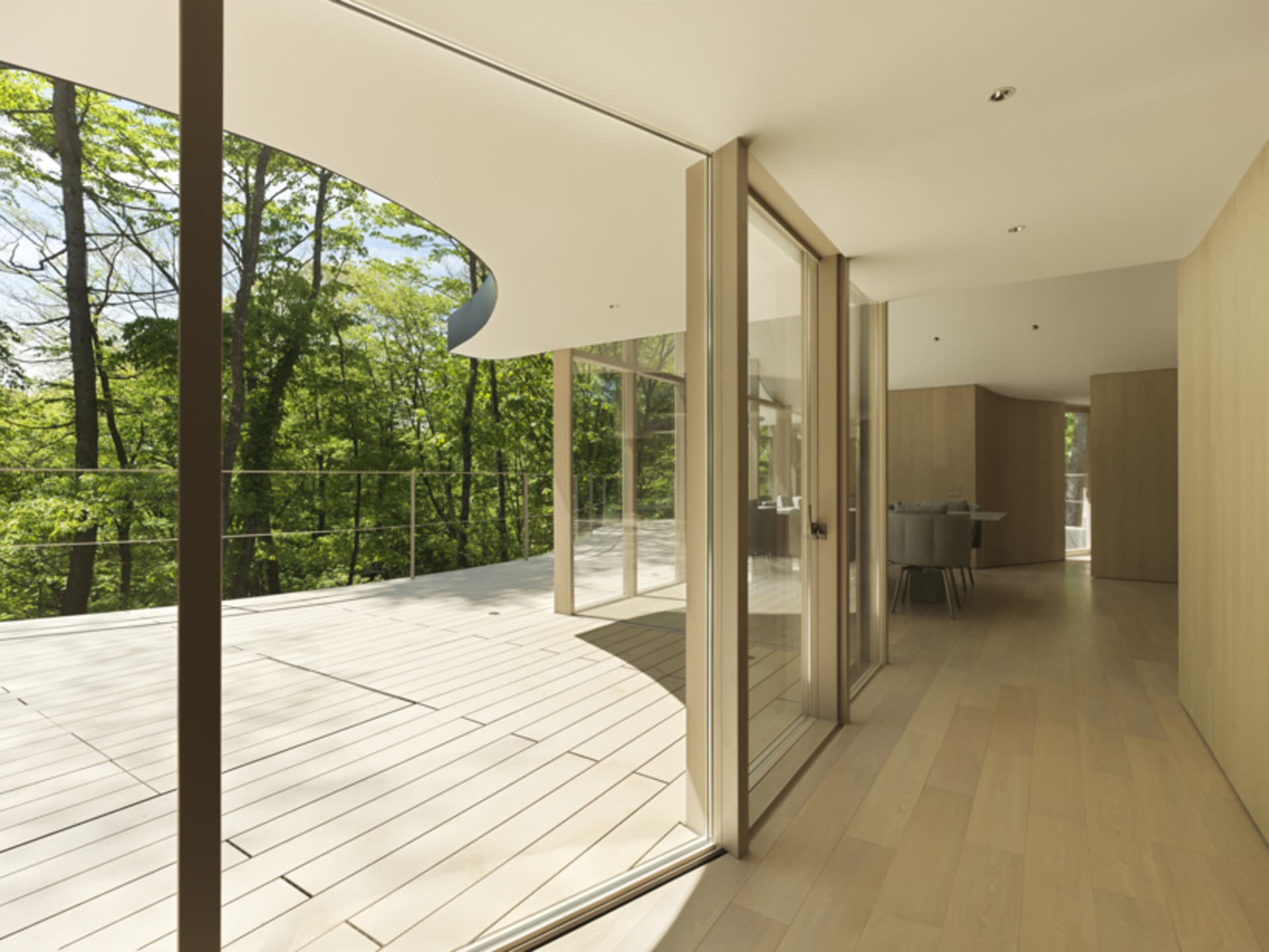 A modern residential deck featuring wood flooring and glass railings.