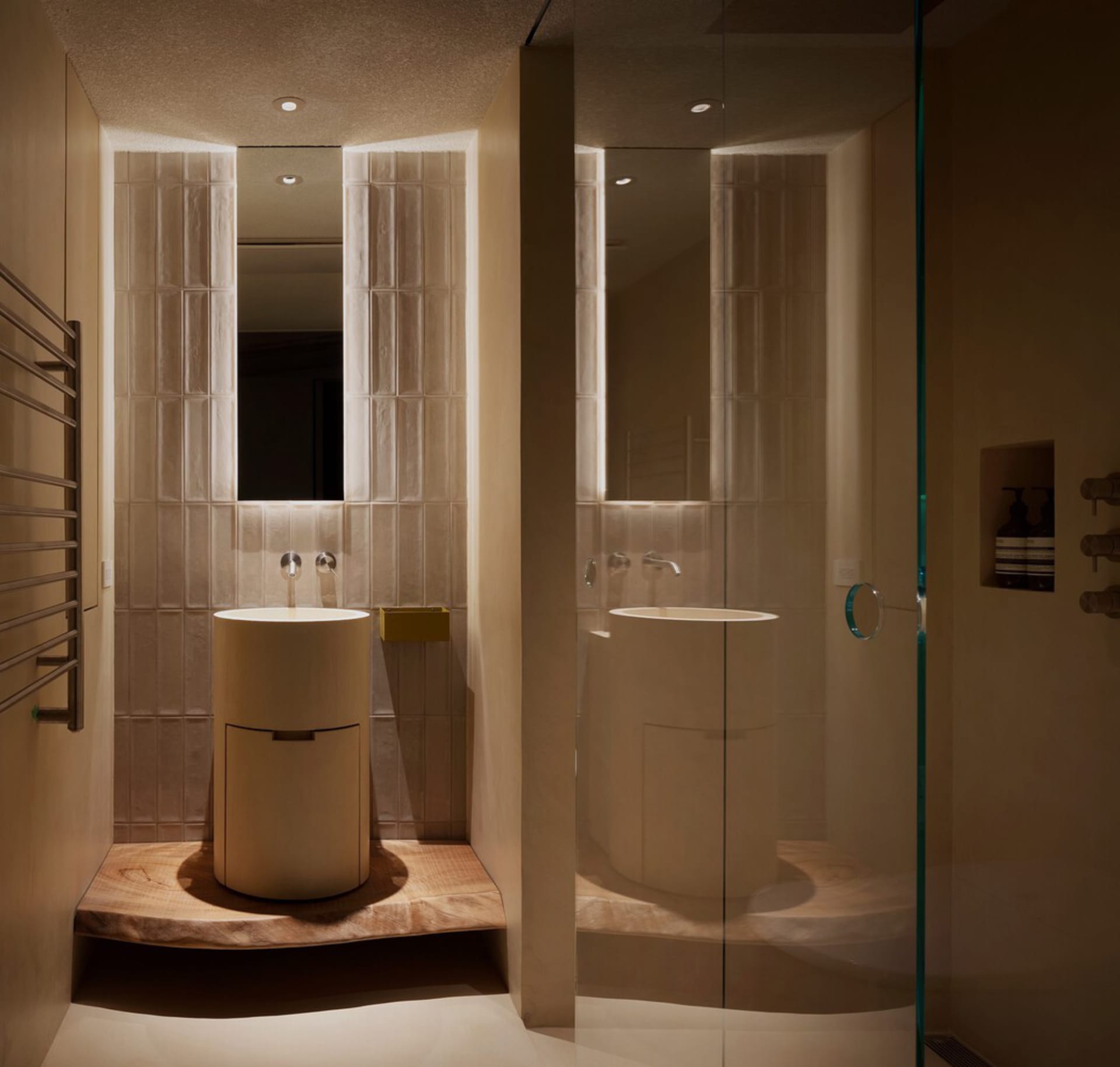 A modern bathroom featuring neutral-toned tiles, a rounded sink, and minimalistic design elements.