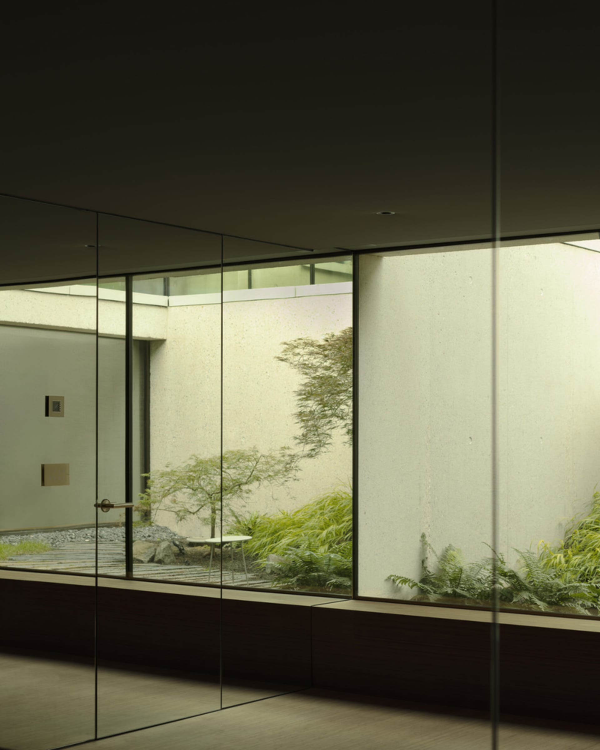 Modern room with glass wall and concrete pavement showcasing framed garden view