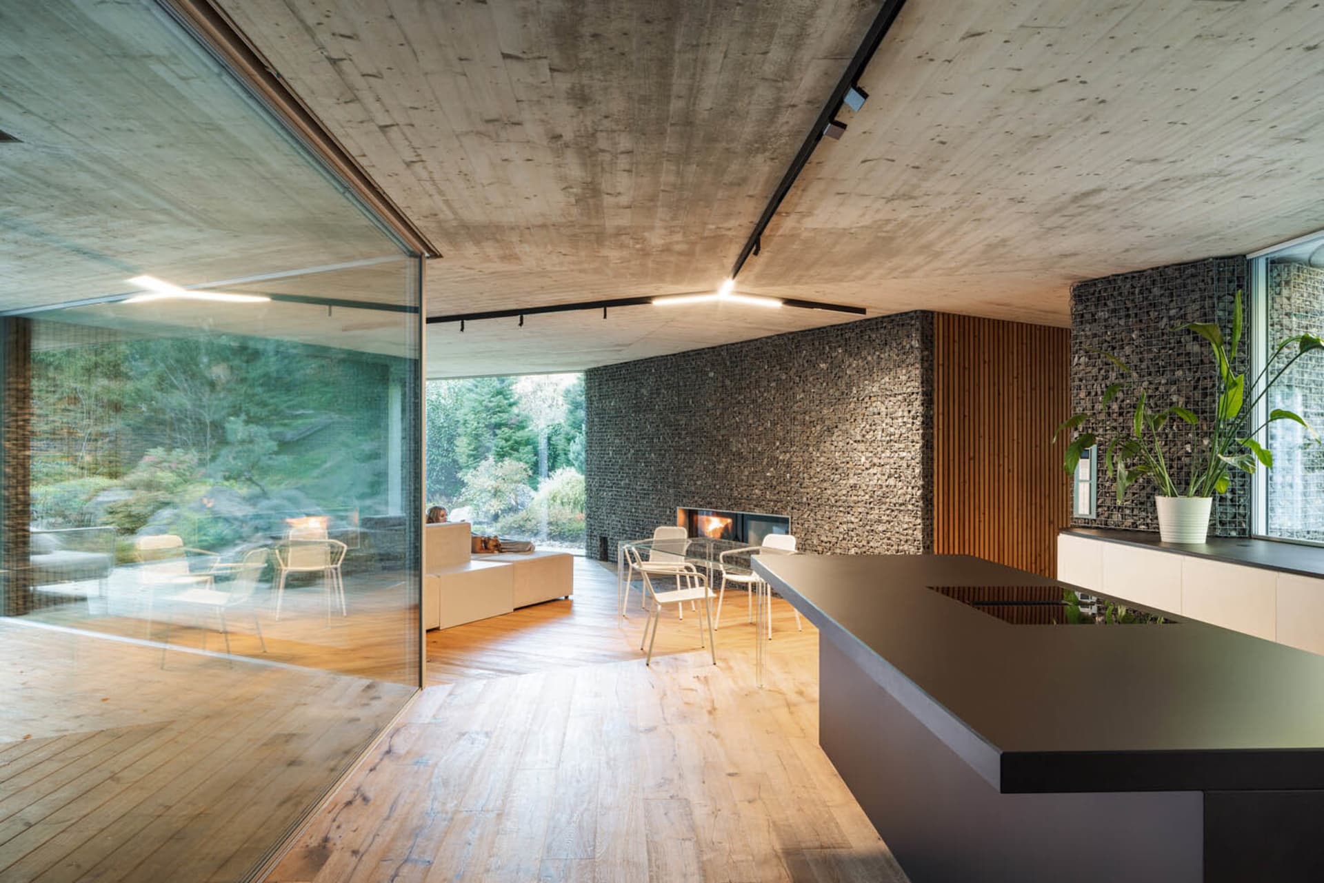 Modern living room with concrete walls, wooden floors, and stone accents