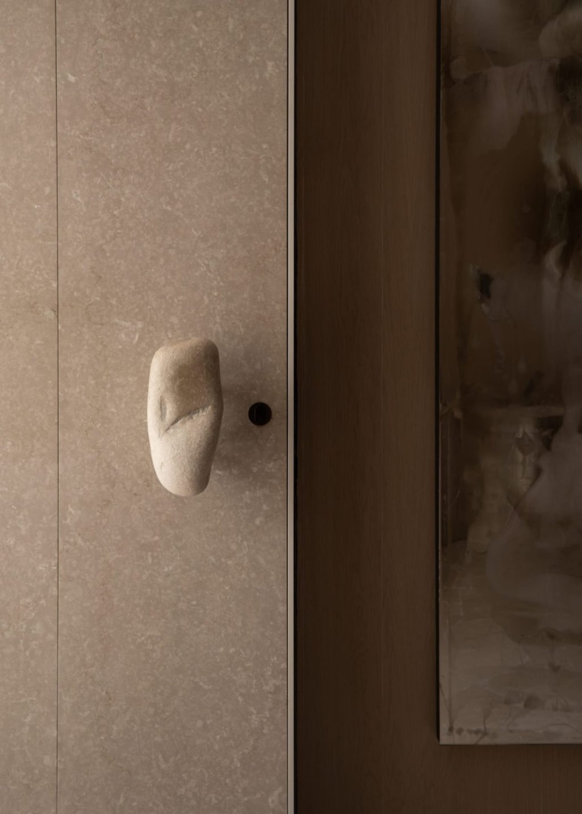 A modern minimalist interior design featuring a stone marble handle on a cabinet or door.