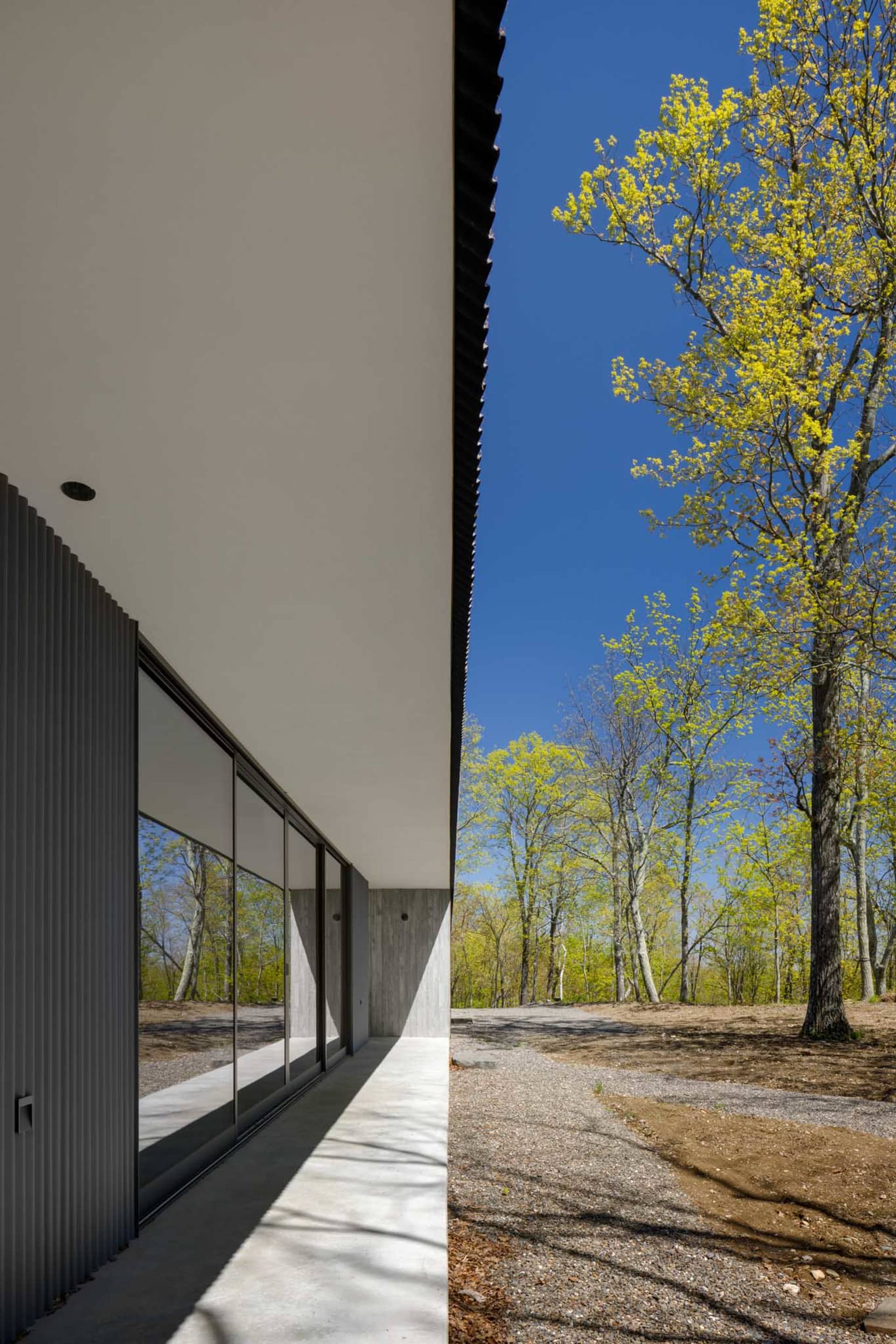 A minimalist residential house exterior featuring modern architectural elements and large glass windows.