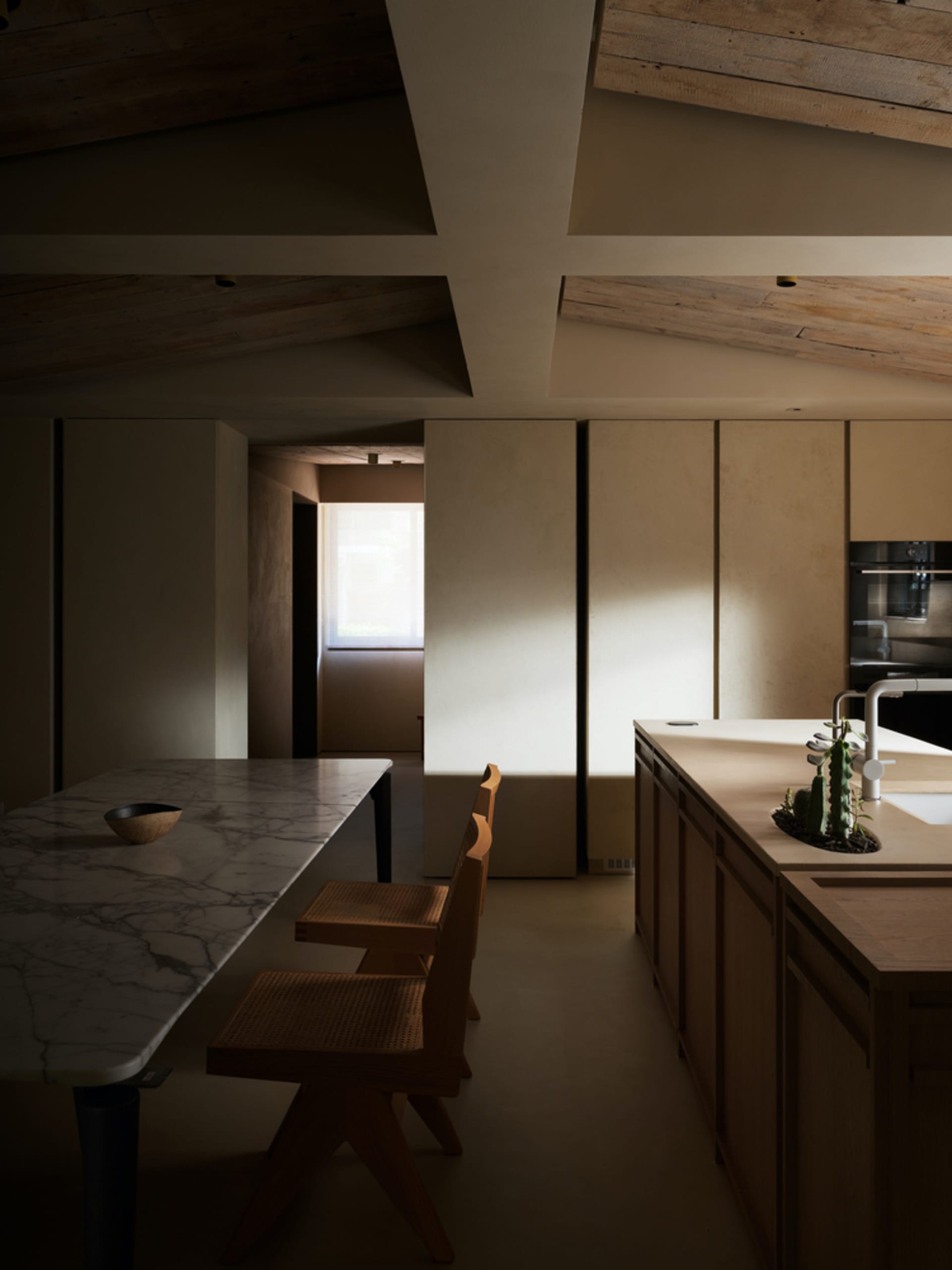 Modern kitchen with minimalist design, featuring a marble countertop and wooden furniture.