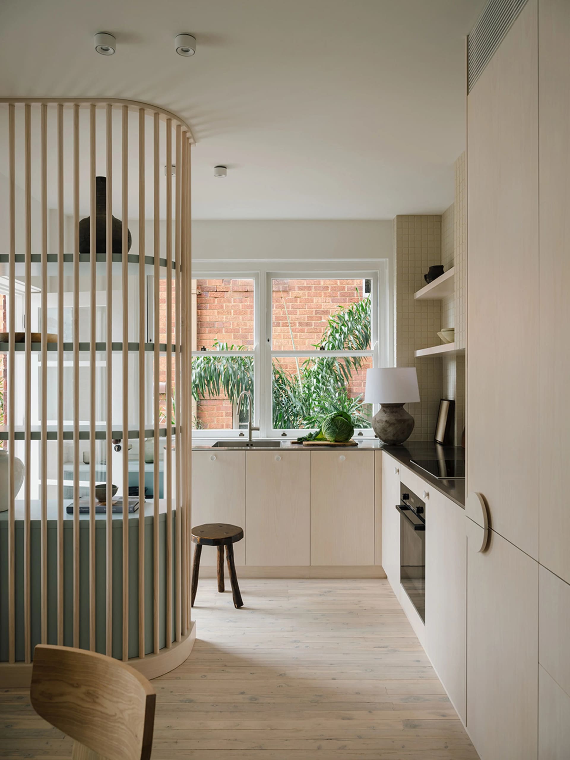 Modern kitchen featuring wooden cabinets, sleek countertops, and a large window overlooking greenery.