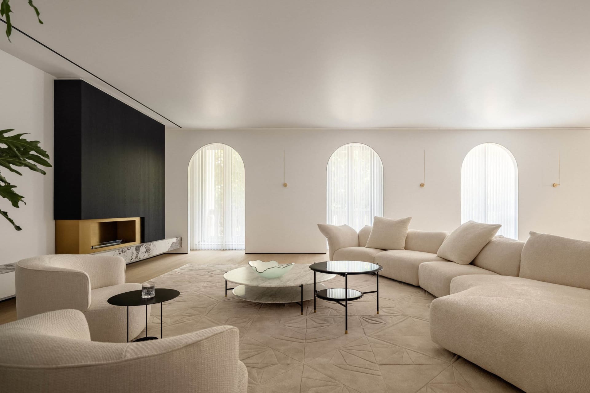 Modern living room with white fabric sofa, arched windows, and marble coffee tables
