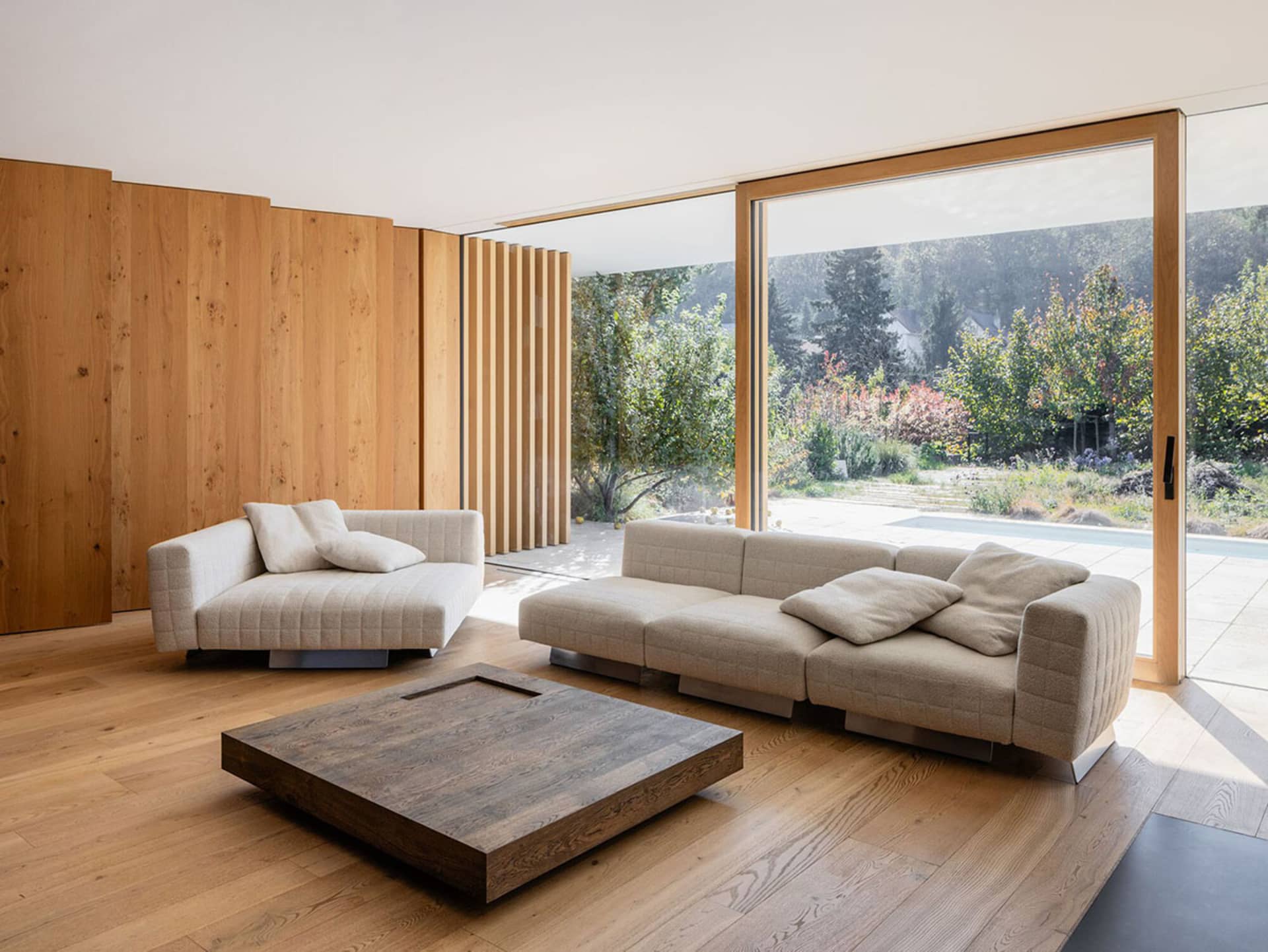 Contemporary living room featuring a modern sofa, wooden floor, and a glass sliding door to the garden.