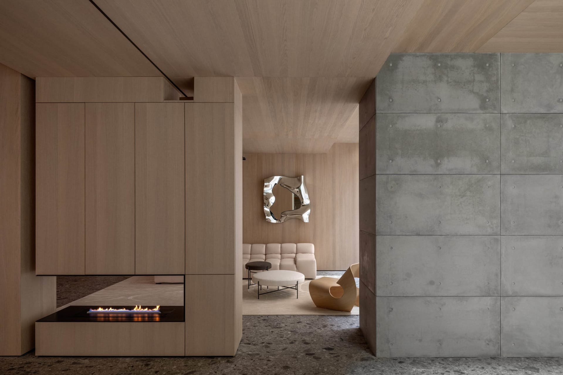 A modern lobby featuring a concrete seating area with wooden accents and minimalist decor.