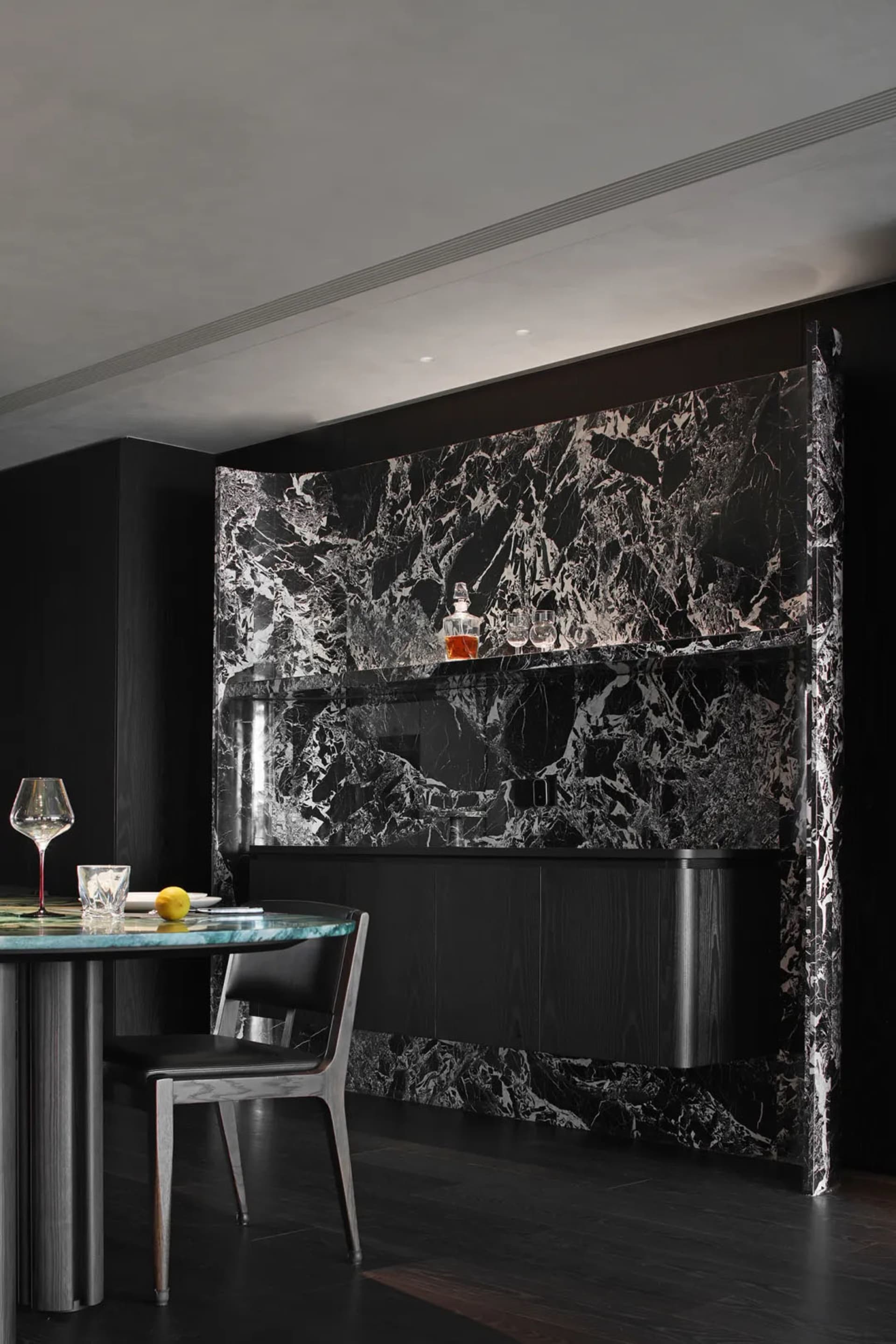 A modern industrial bar counter made of marble with black and white veins, featuring a sleek design with a single chair and a