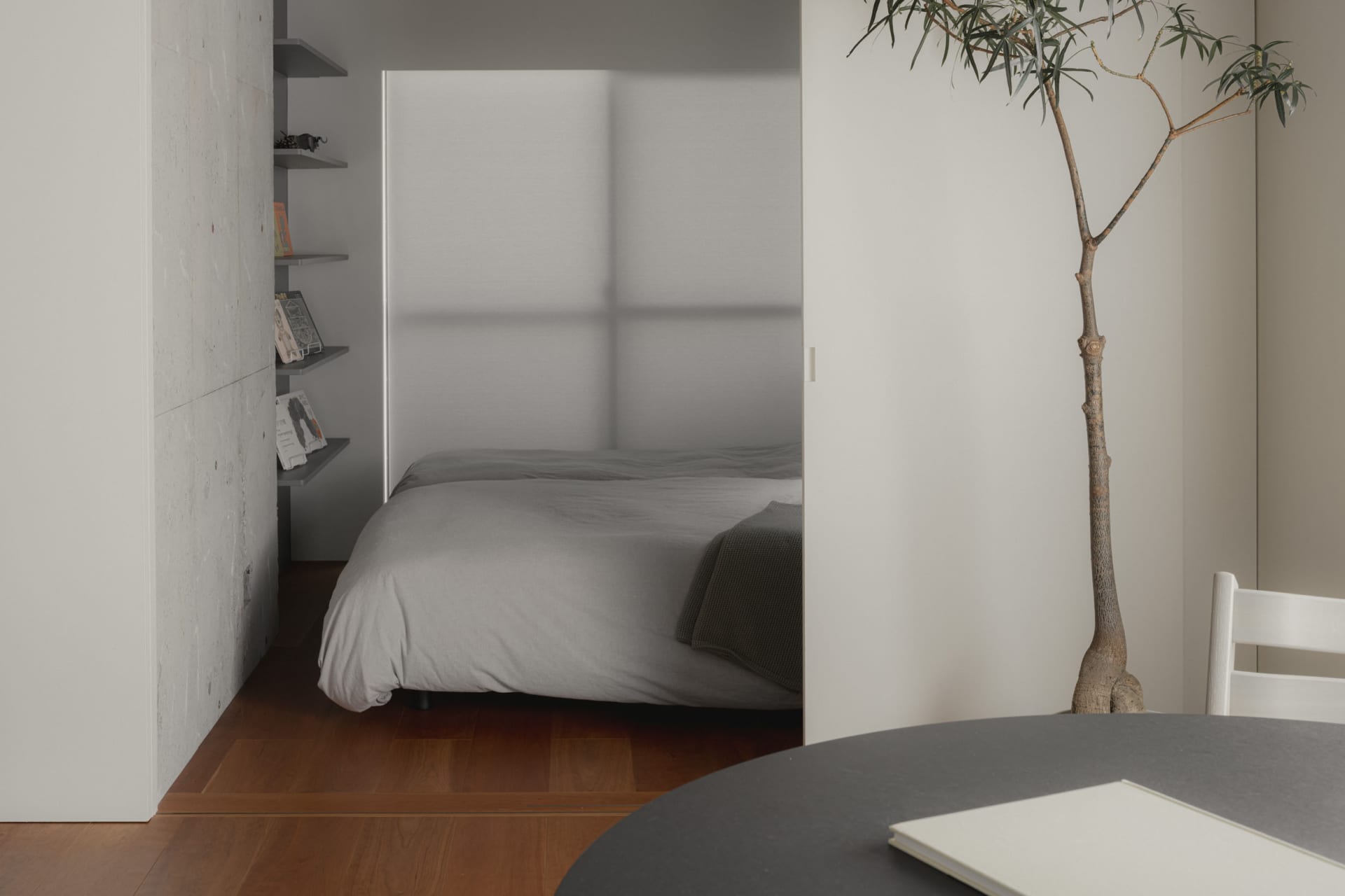Modern, minimalist bedroom with concrete walls and a bed.