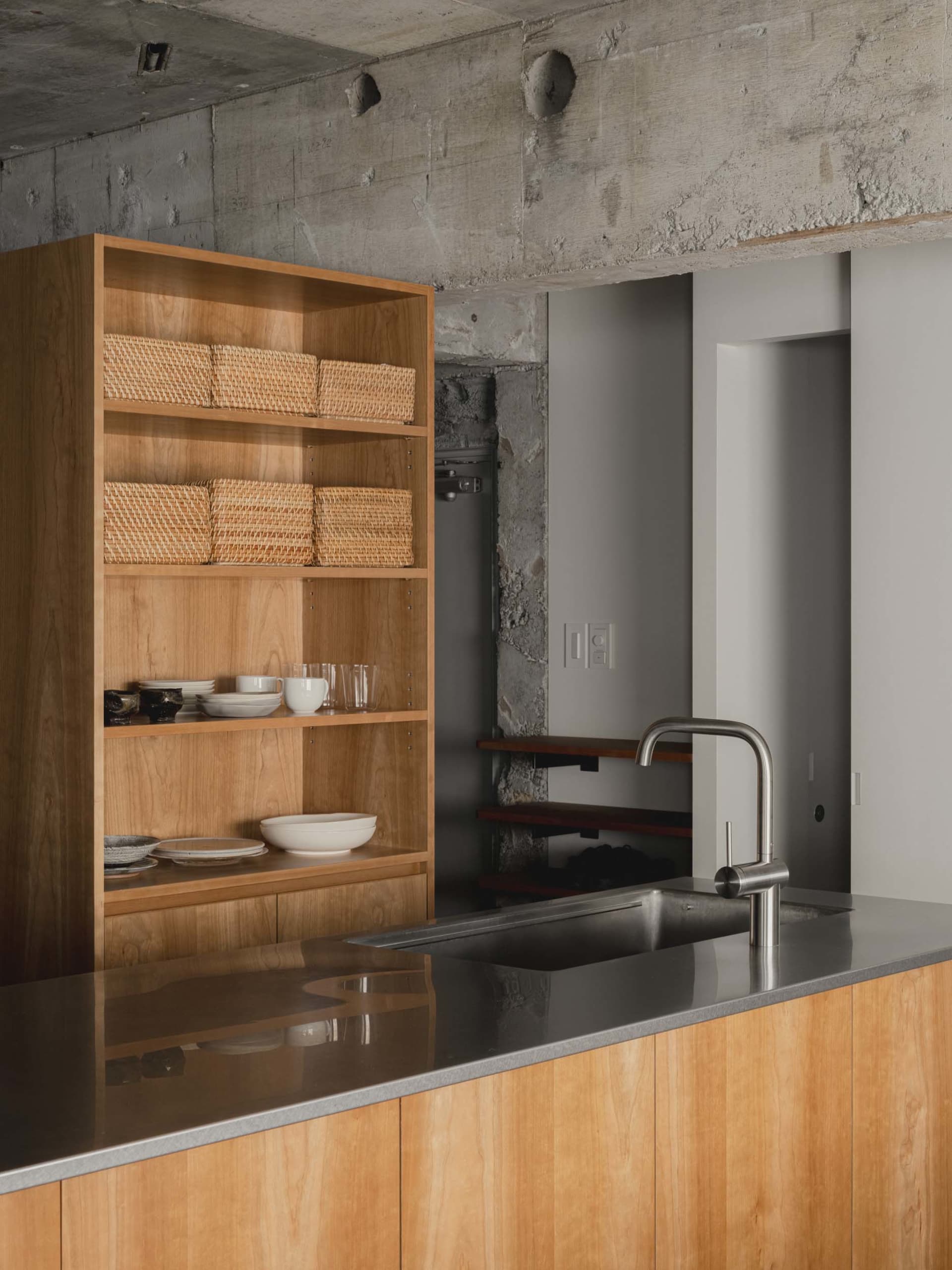 Modern minimalist kitchen with wooden cabinets and concrete wall.