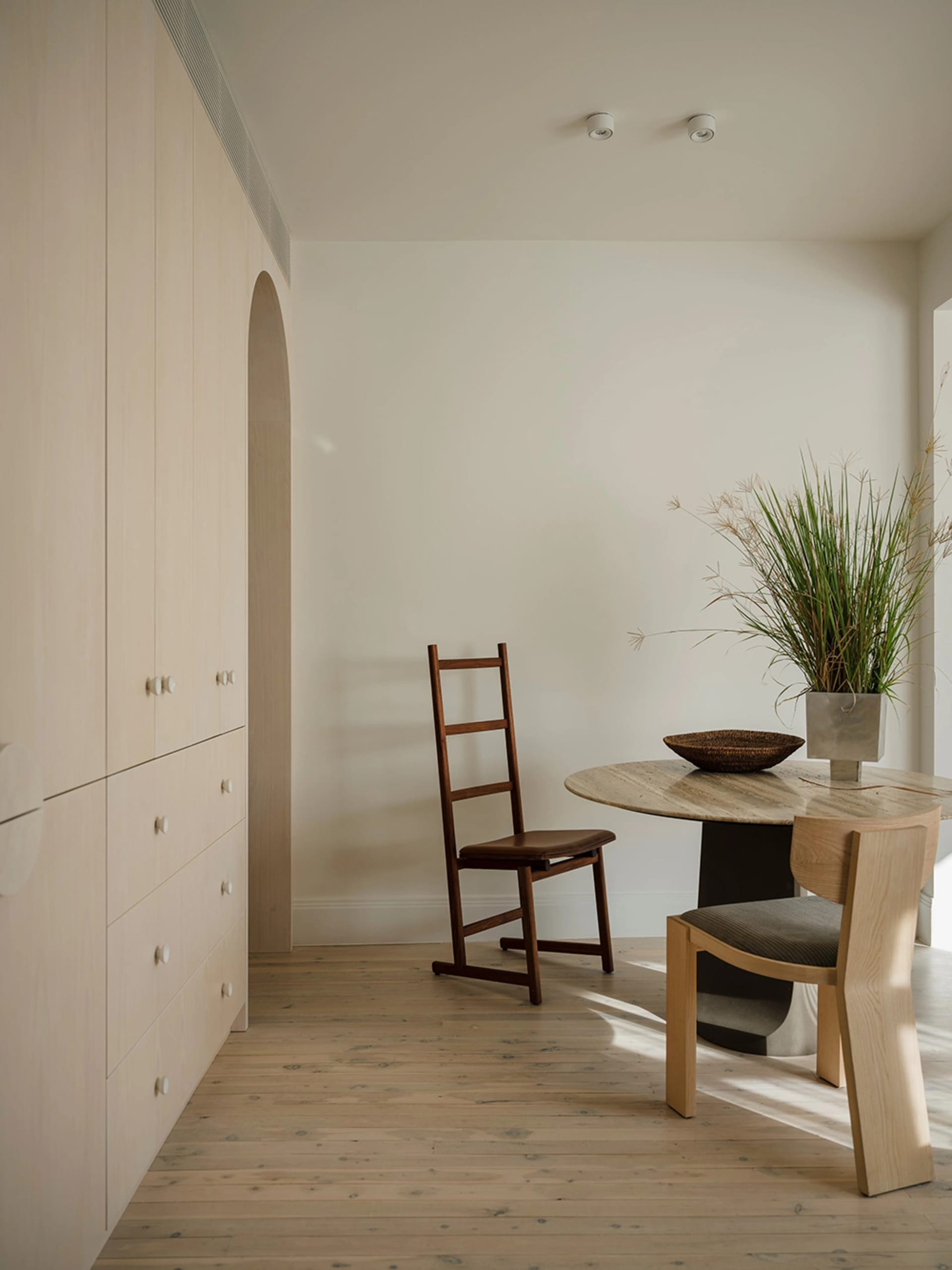 A minimalist space featuring a wooden chair, marble table, and minimalist design elements.