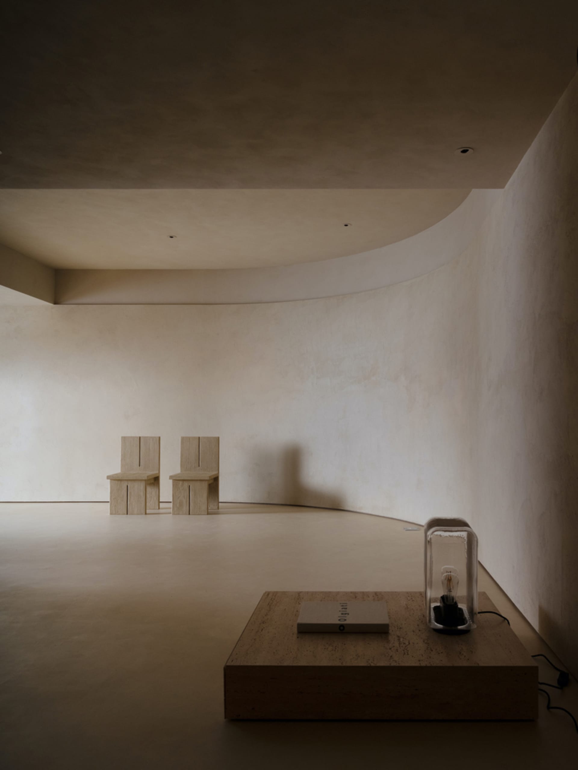 A modern minimalist interior space featuring concrete furniture and flooring.