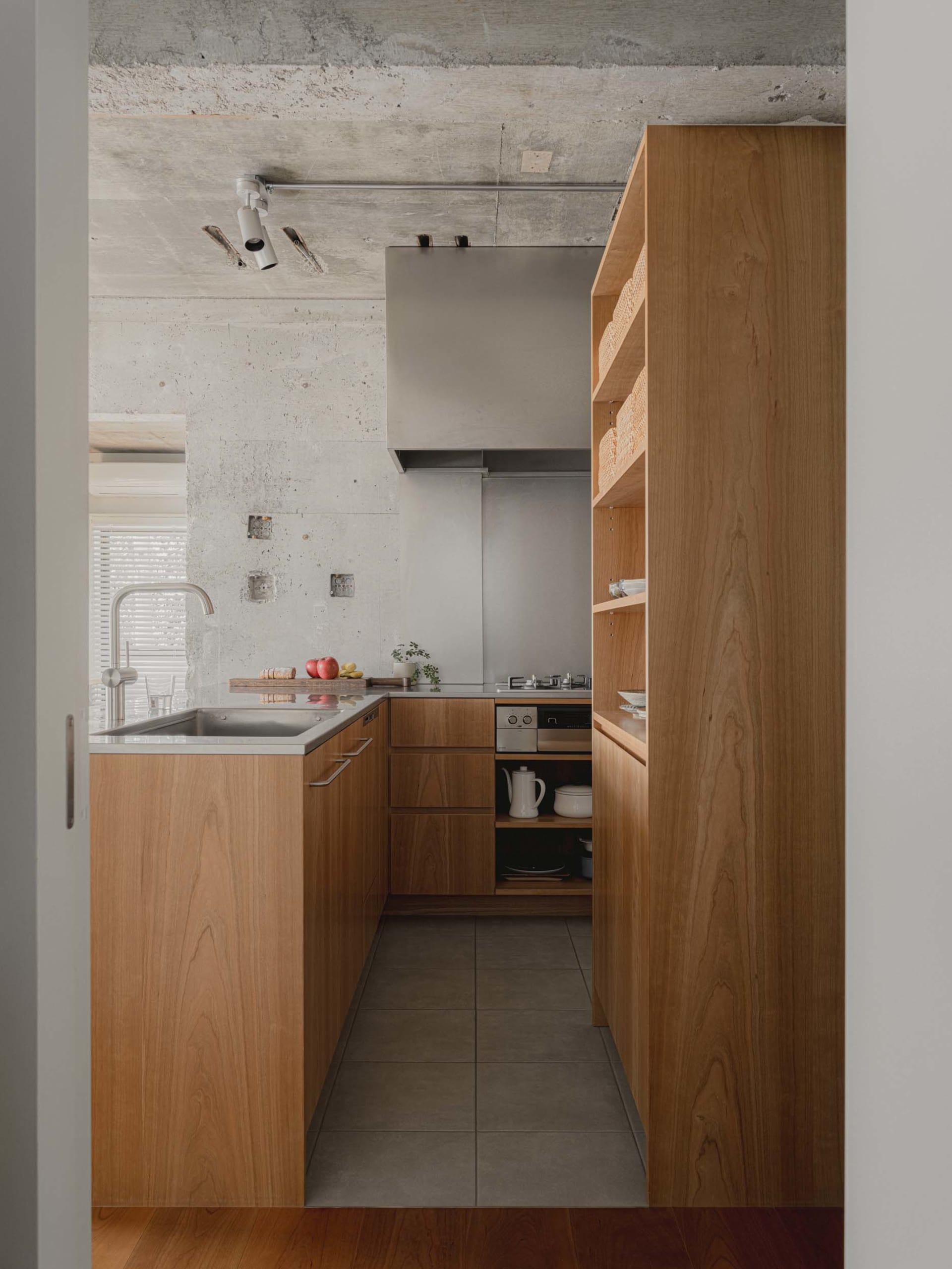 A modern kitchen with wooden cabinets and a concrete ceiling