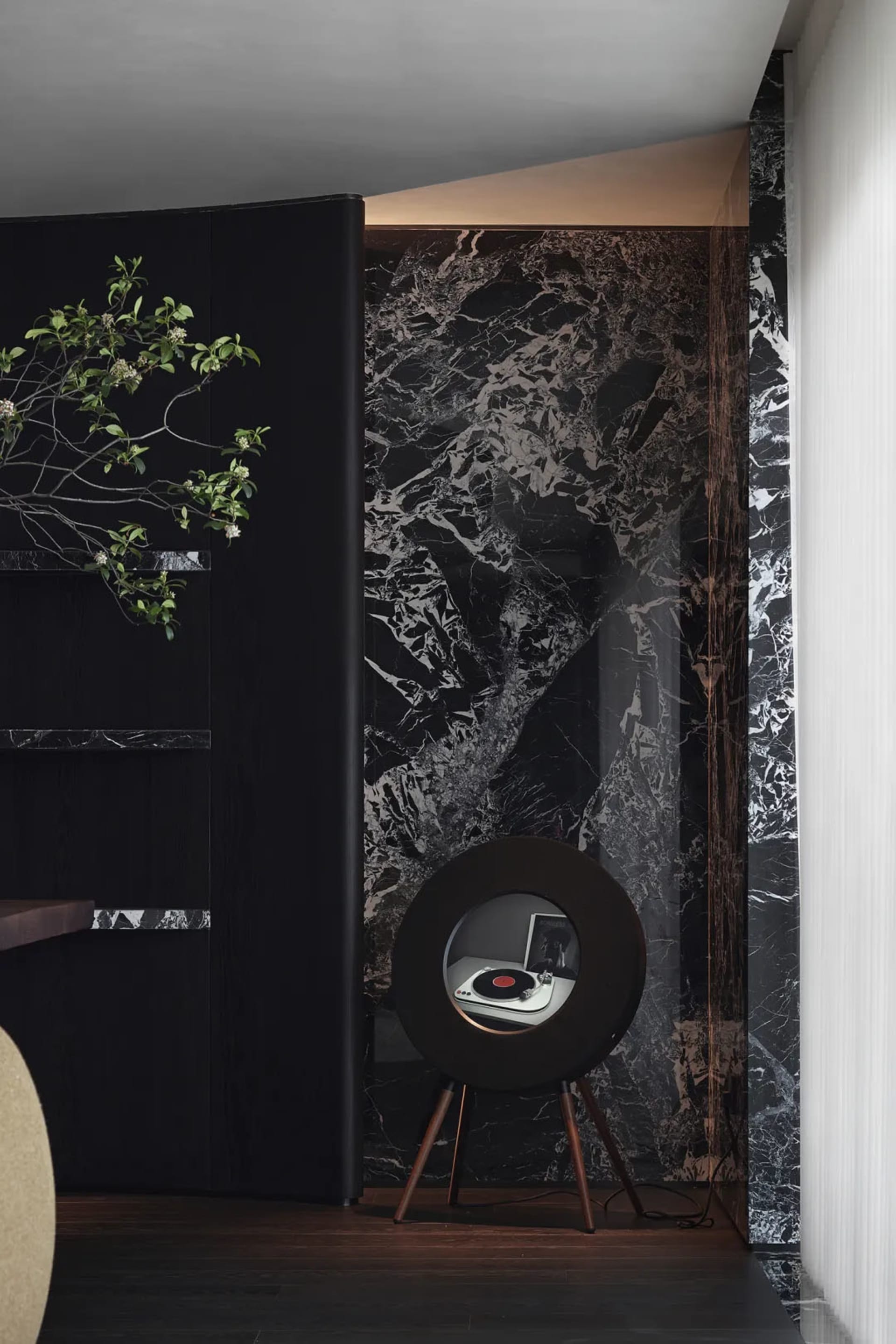 A modern living room featuring marble walls and a sleek, round speaker.