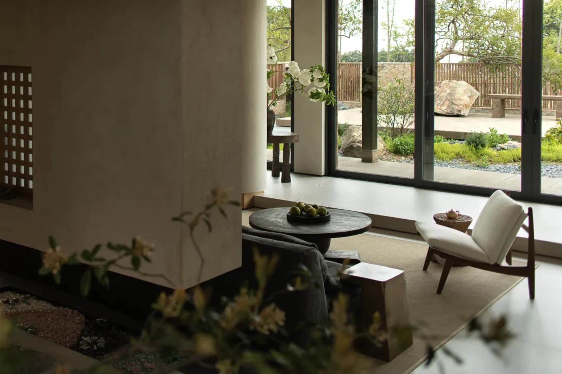 A minimalistic living room with concrete walls and a view of a garden.