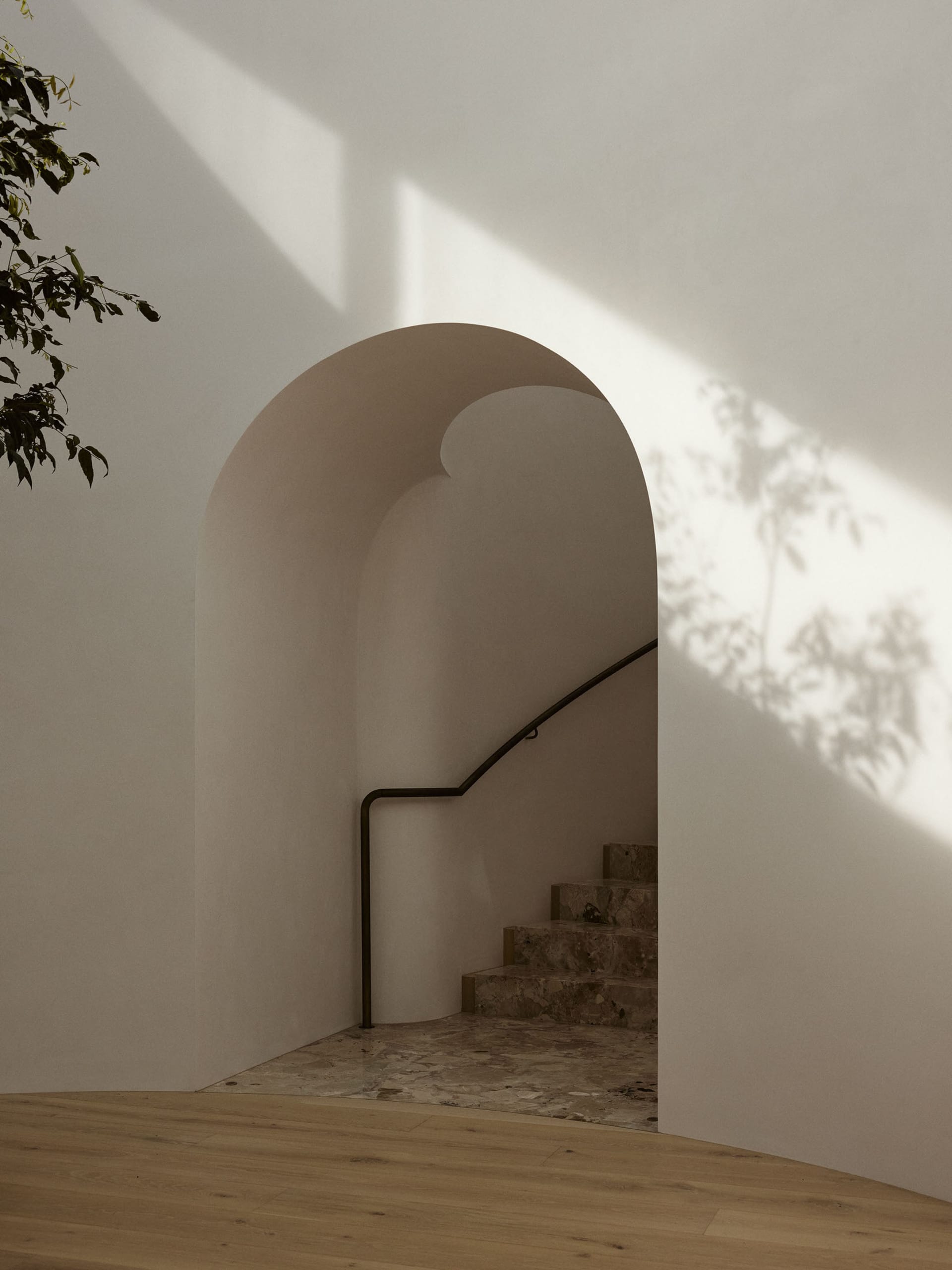 Modern, minimalist staircase with marble steps and handrail in a light-filled space.