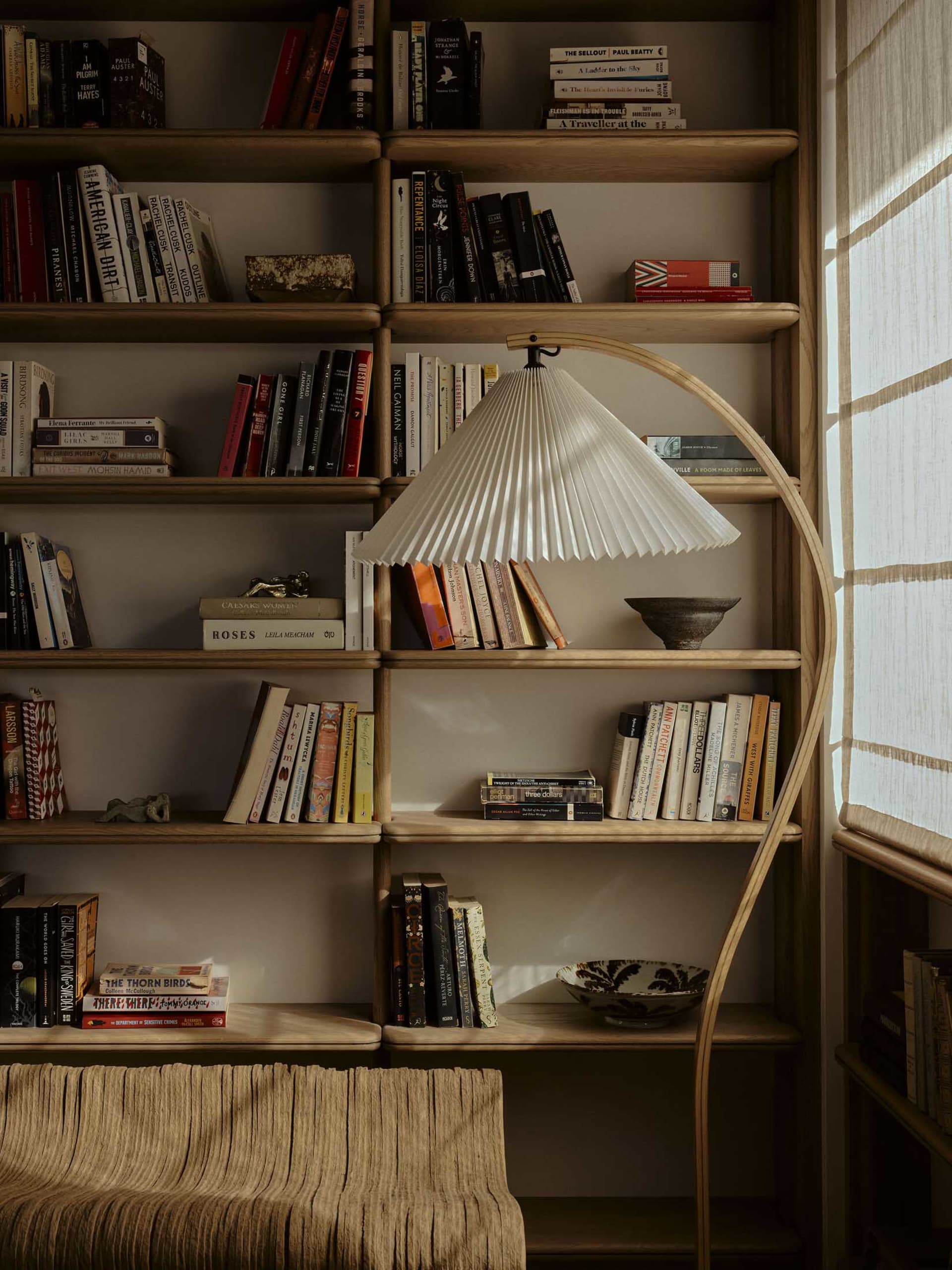 A modern minimalist bookshelf filled with books and a beautifully designed floor lamp.