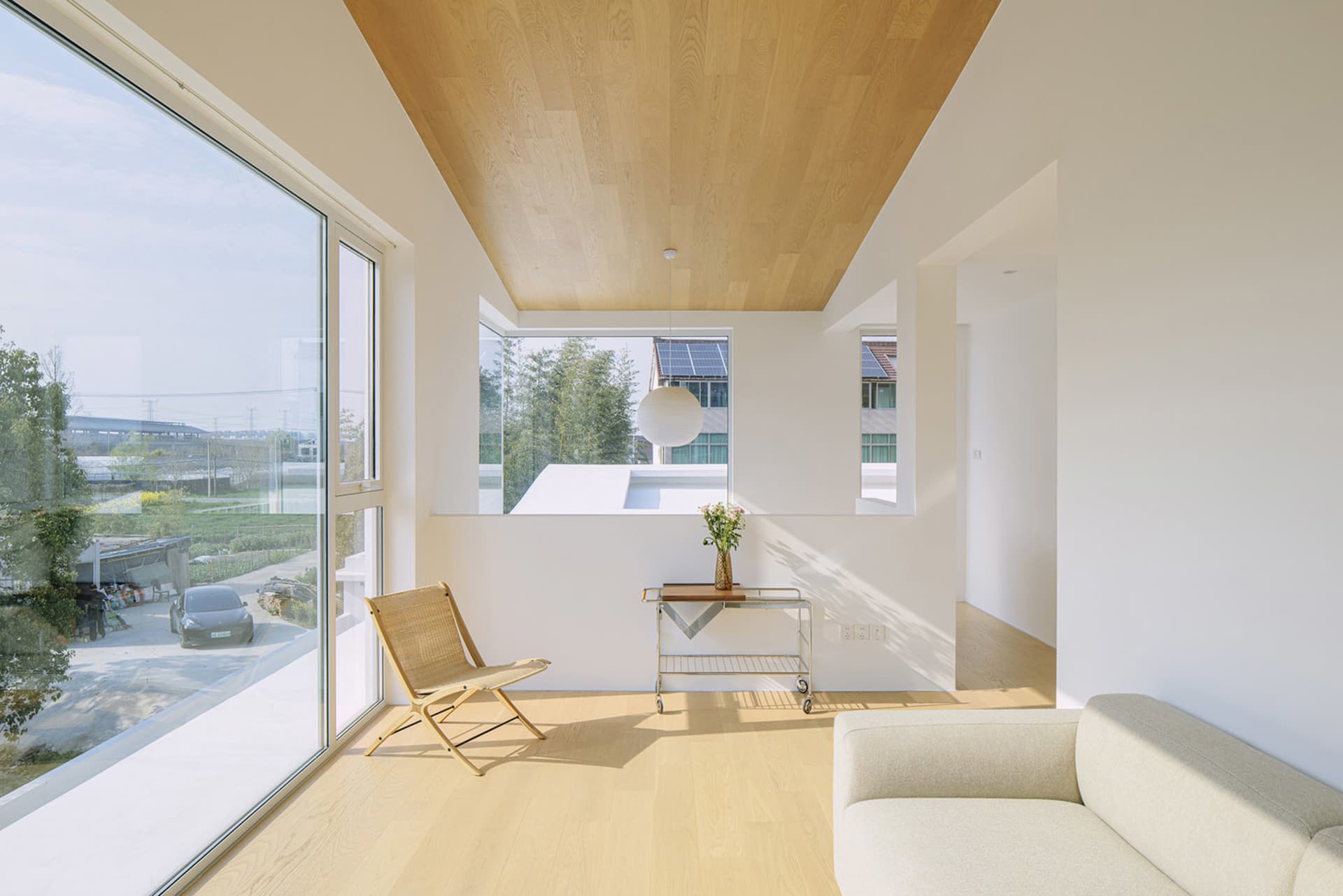 A minimalistic living room featuring wood elements and a floor-to-ceiling window.