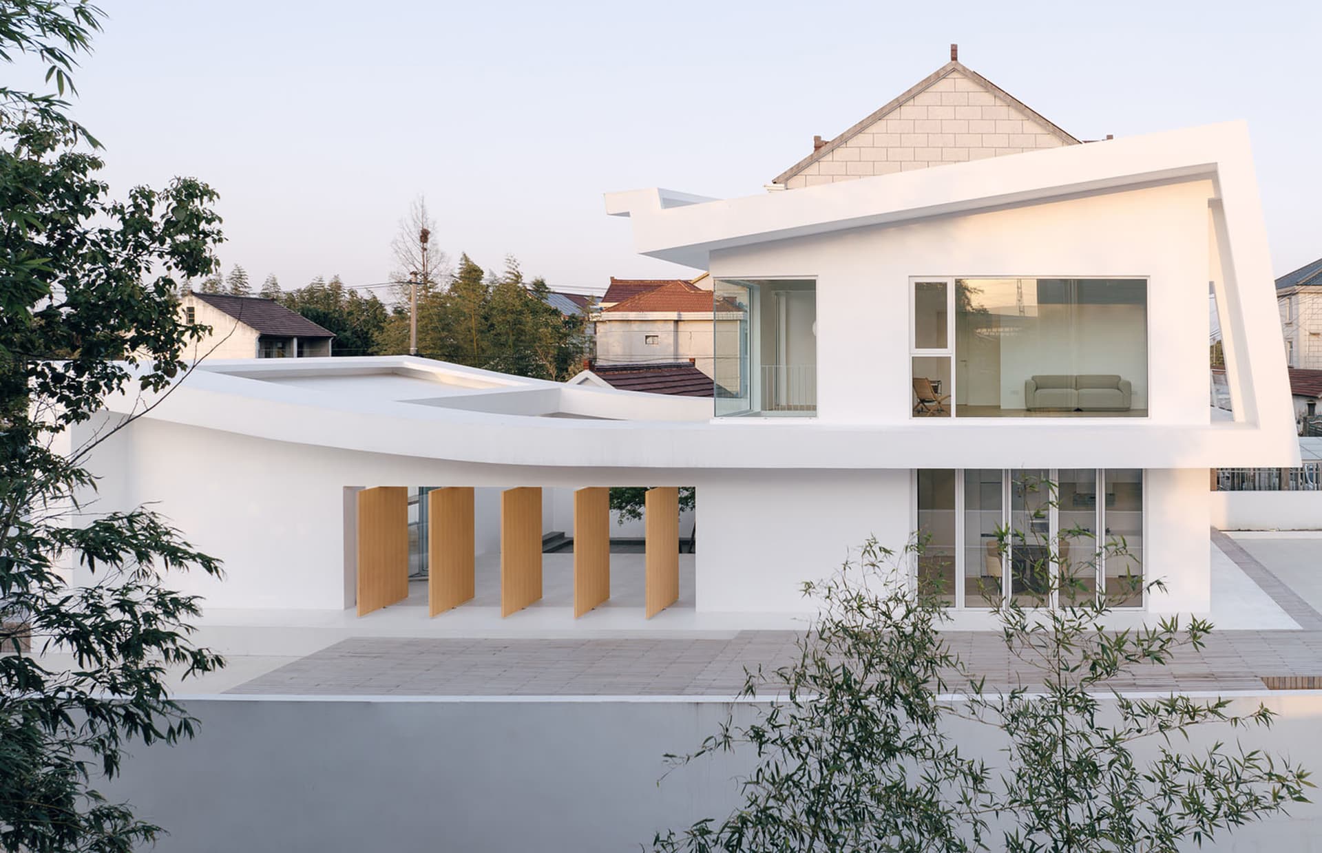 Modern house exterior with white painted walls, large glass windows, and wooden accents.