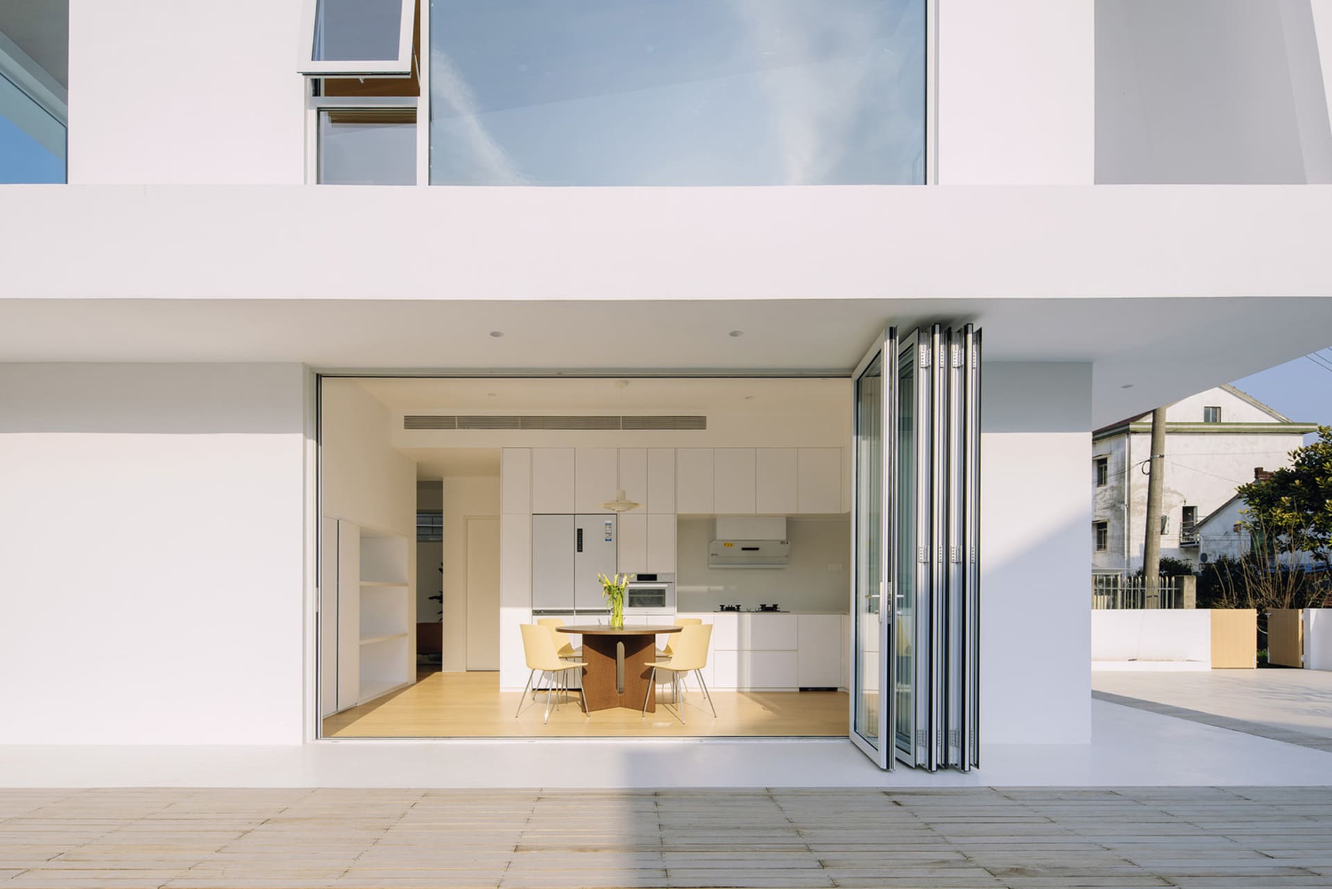 Modern residential kitchen featuring a wooden dining table and chairs, white cabinetry, and a view of the exterior.