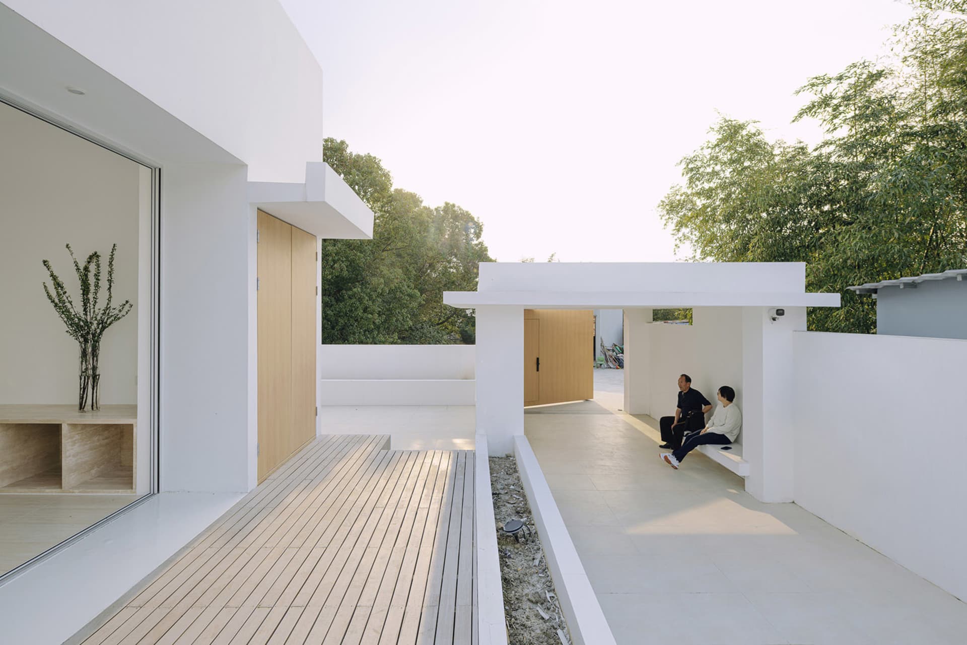 A modern house with white walls and a wooden deck.
