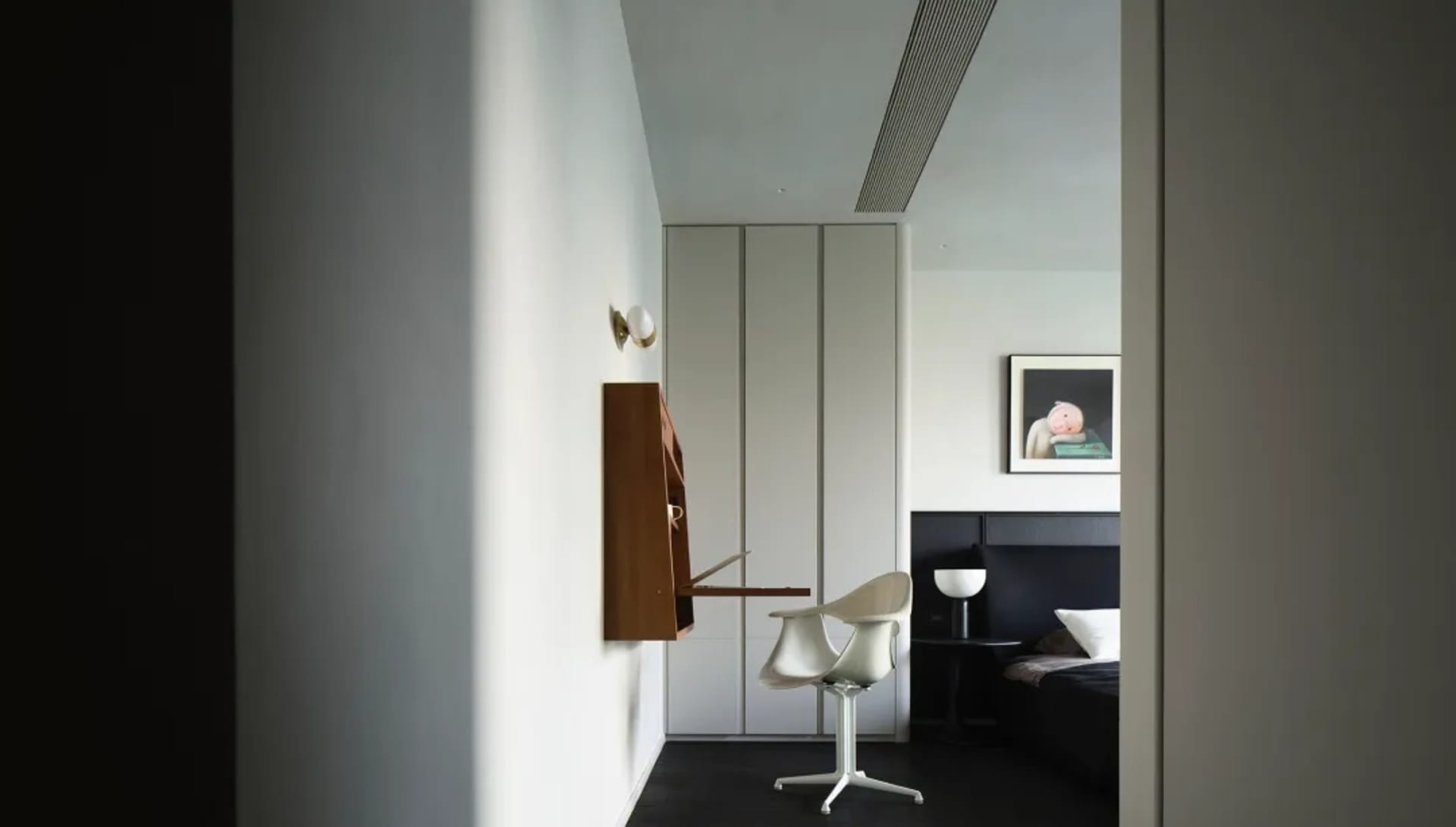 Modern minimalist bedroom with concrete floor, black furniture, and white elements.