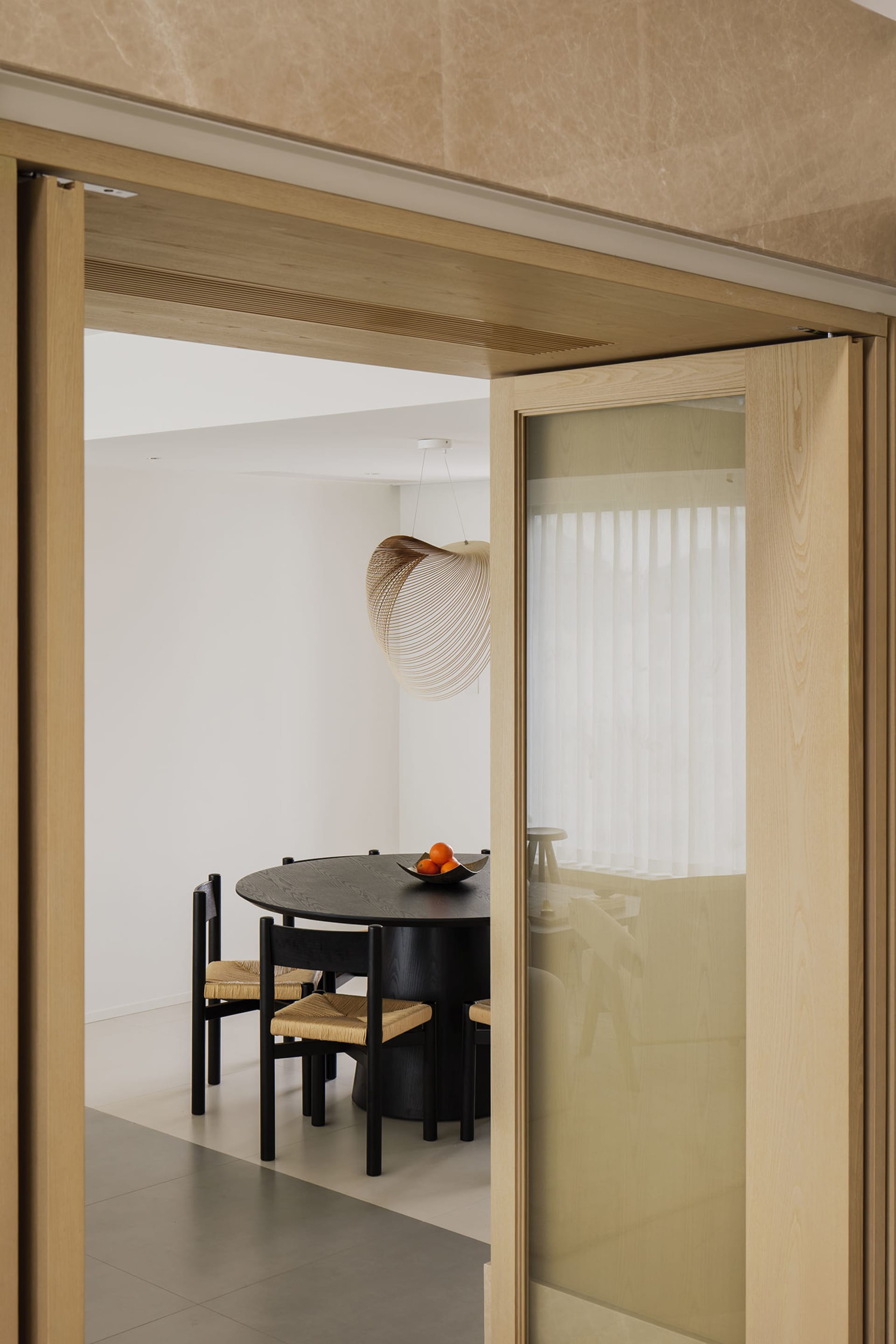 A modern dining room featuring wooden furniture and a round table with hanging lamps.