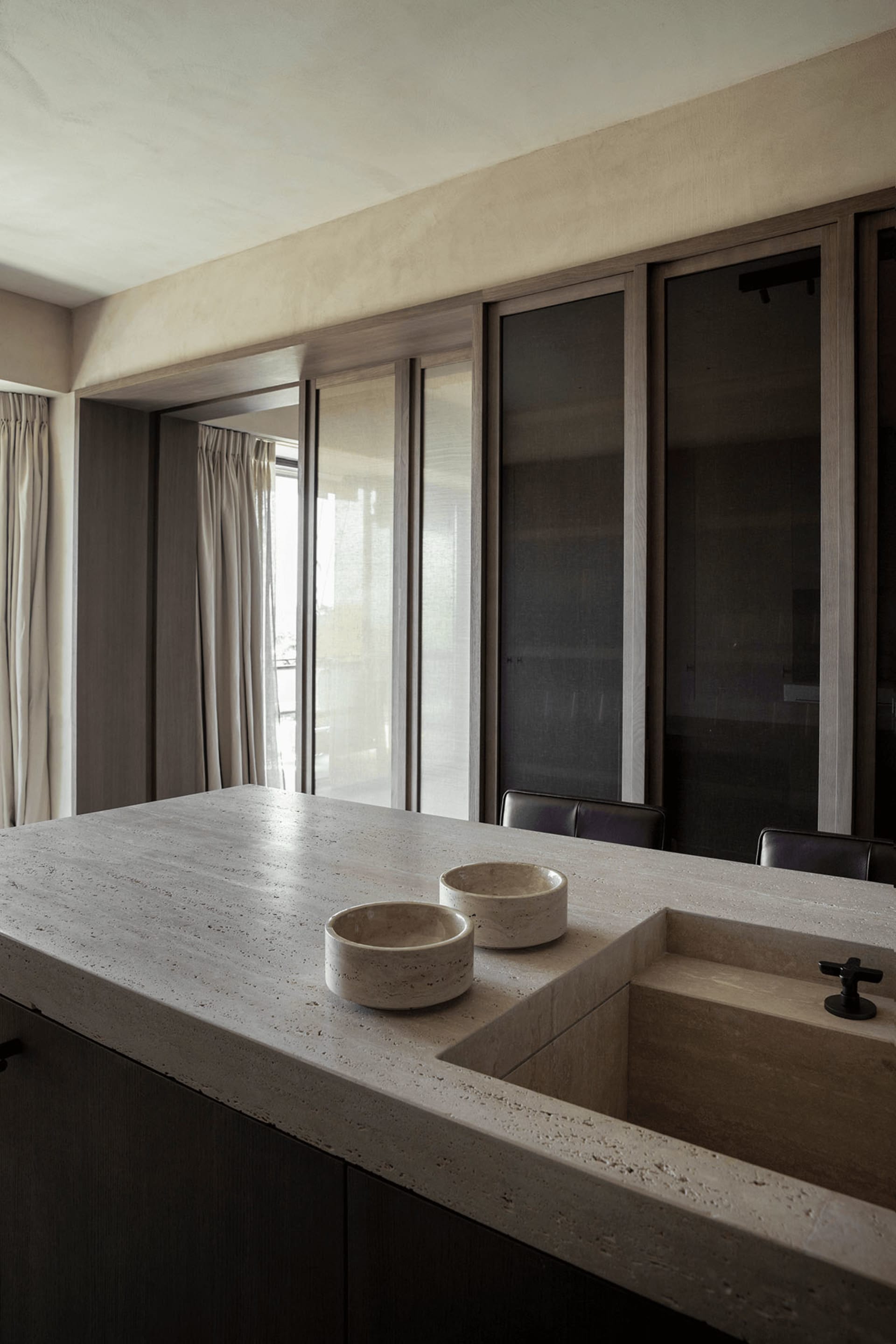 A modern kitchen interior with a concrete countertop featuring a built-in sink and two bowls.
