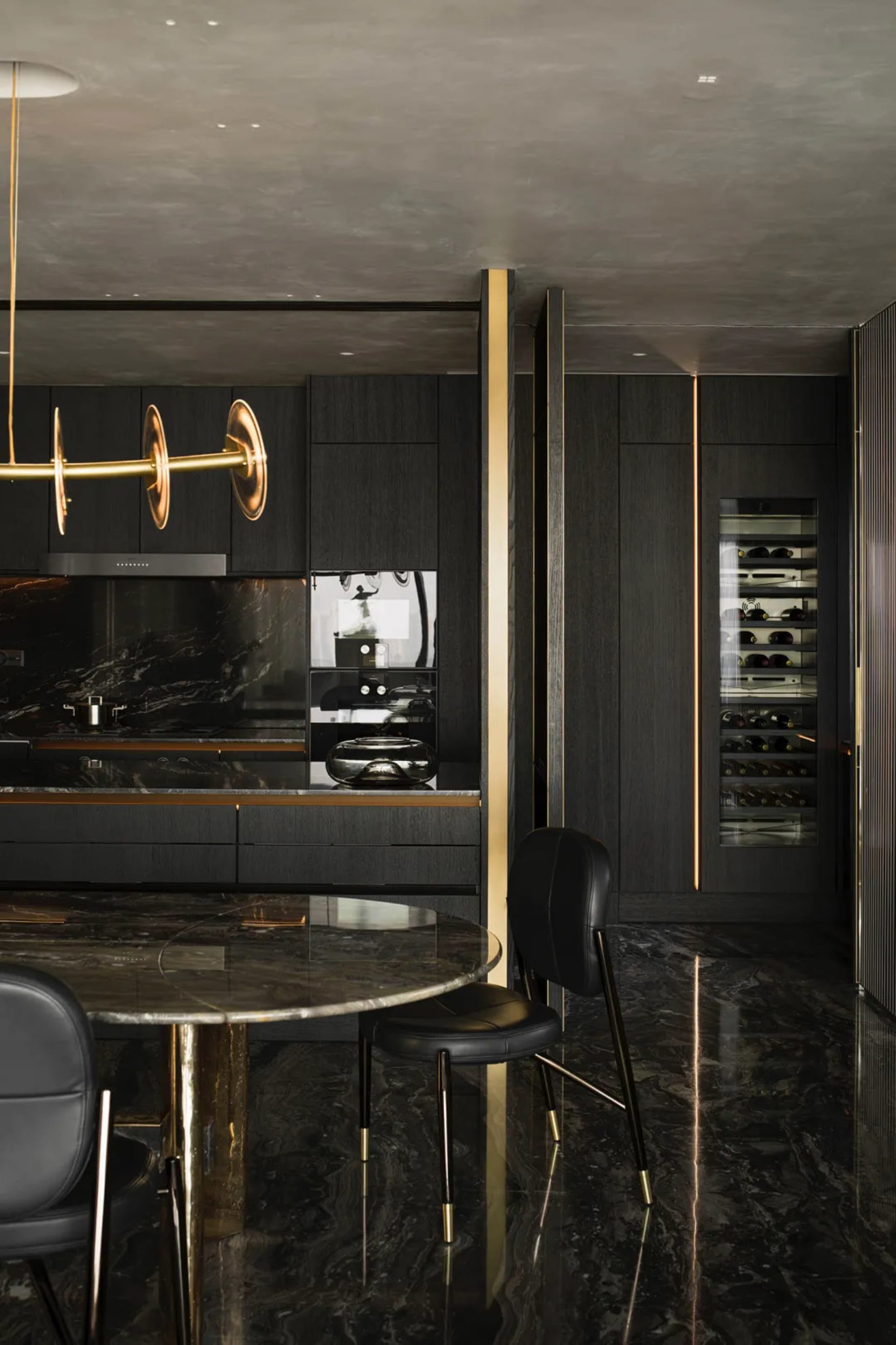 Modern luxury kitchen with black marble countertops, black and gold cabinetry, and minimalist design