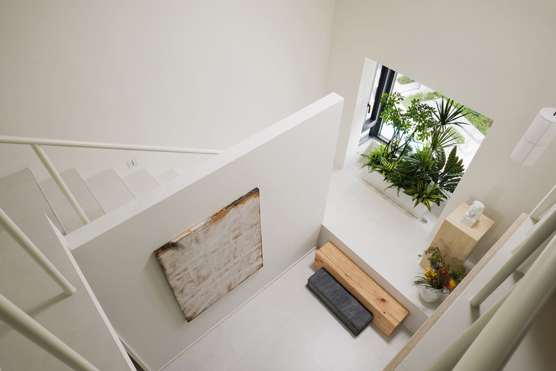 A minimalist, white interior space with raw wood, concrete, and metal elements.