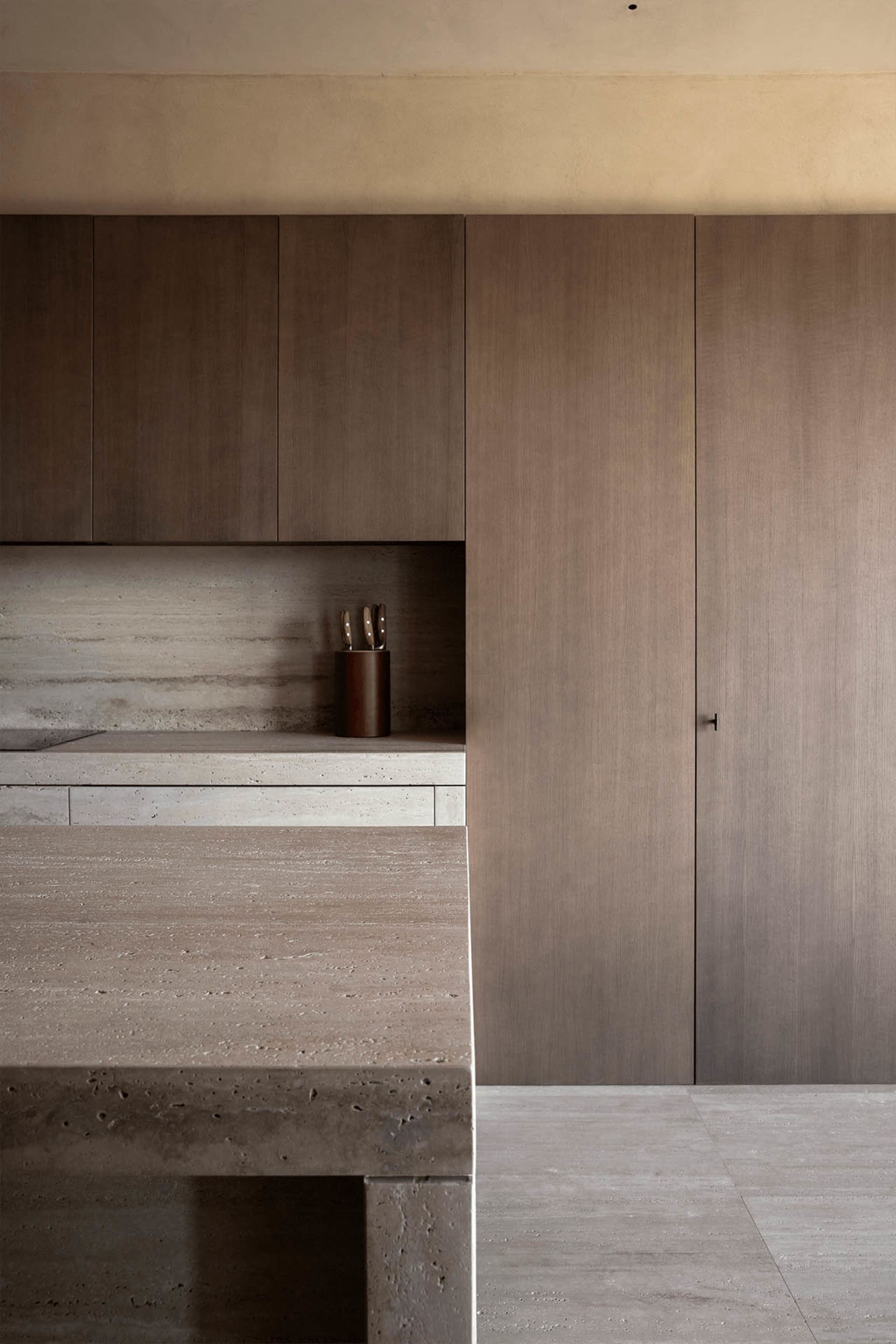 Modern, minimalist kitchen featuring concrete countertops and backsplash.