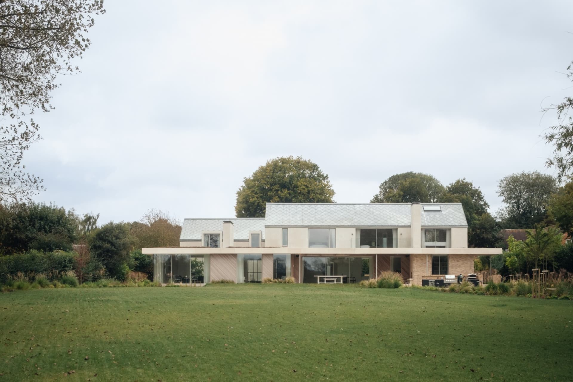 A modern residential house featuring glass walls and beige brick exterior.