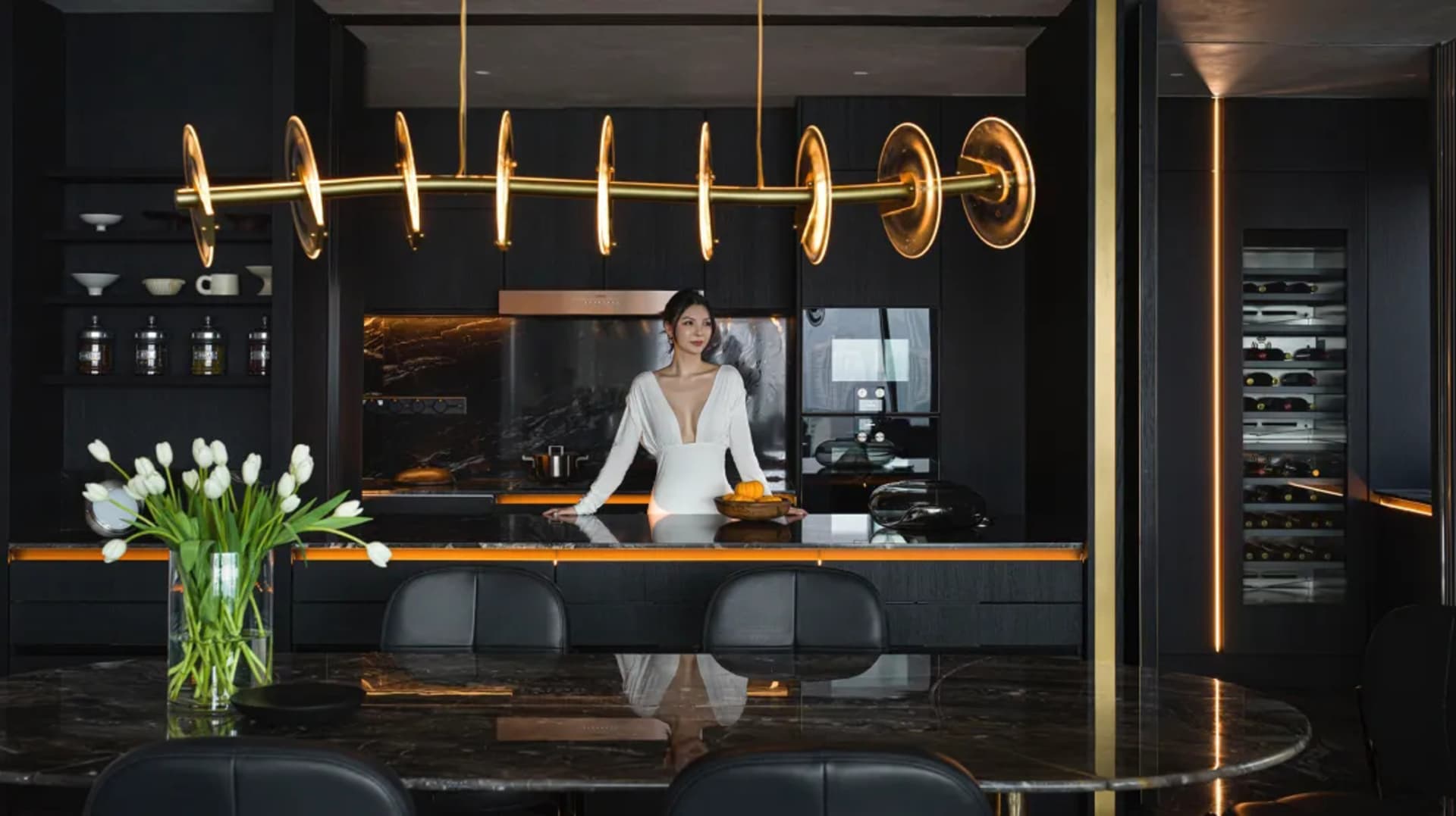 A stylish modern residential interior with black marble countertops and black wooden cabinets.