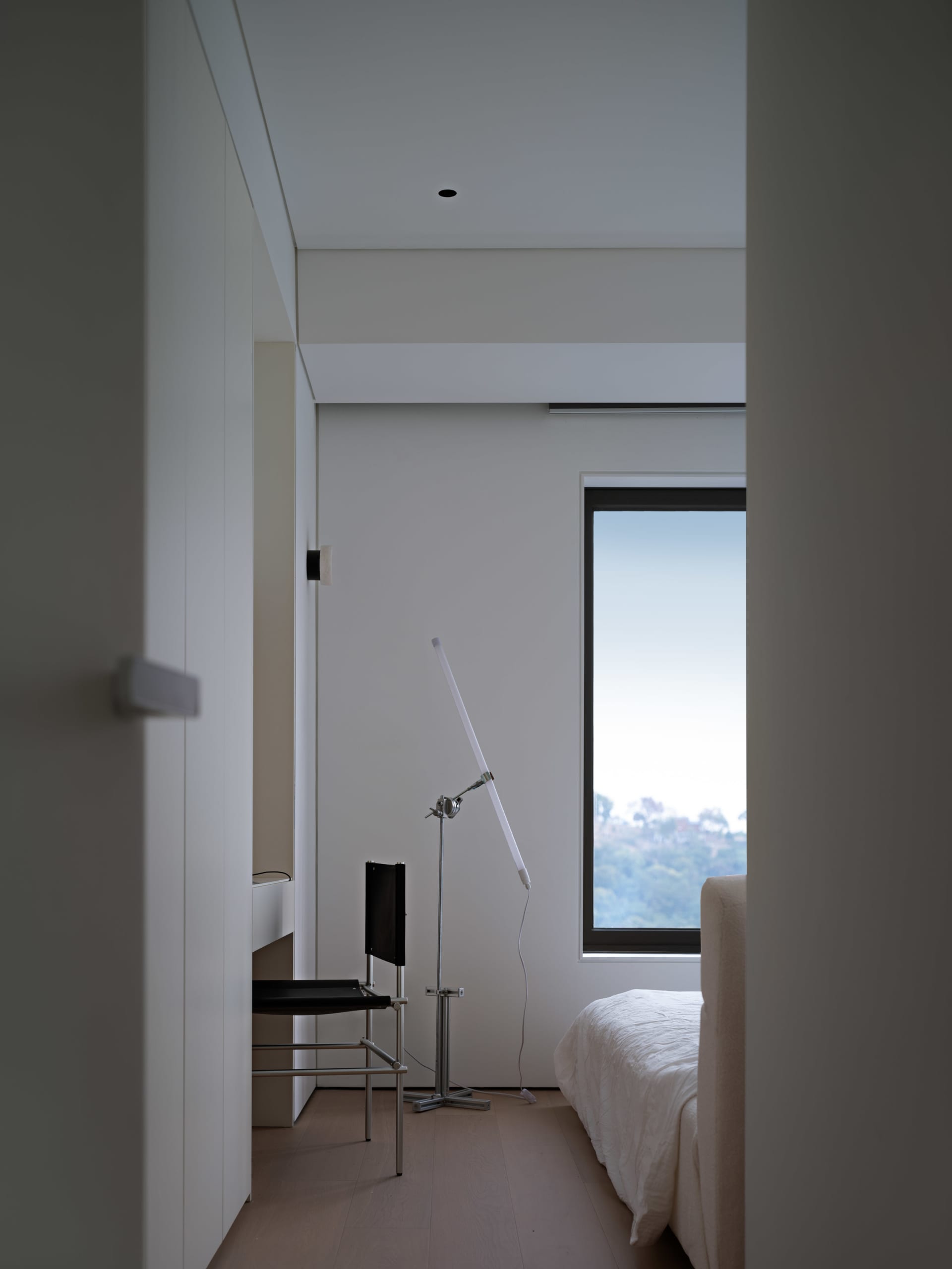 A minimalist bedroom with a wooden floor and a large window.
