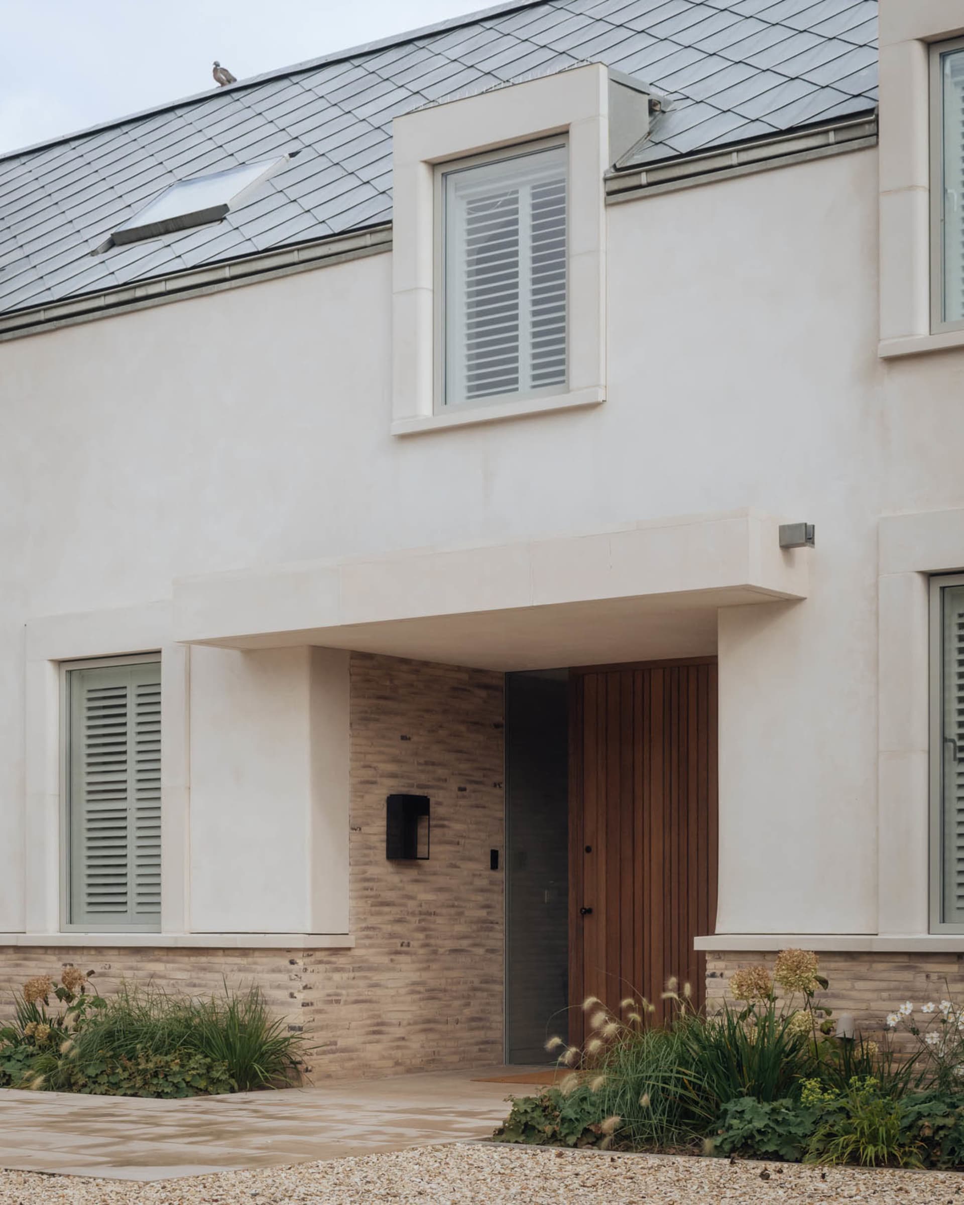 Modern residential home with stucco exterior featuring a wooden door and greenery.