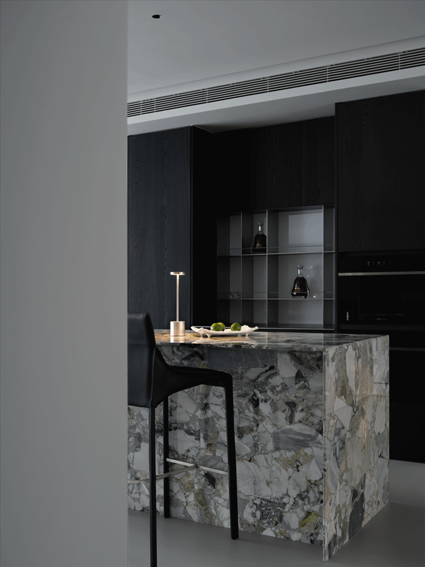 Modern kitchen with marble countertop and black cabinets.