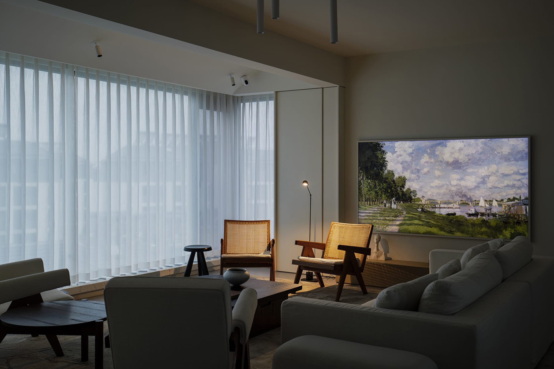 A well-lit, modern living room featuring fabric furniture and curtains, with a large painting on the wall.