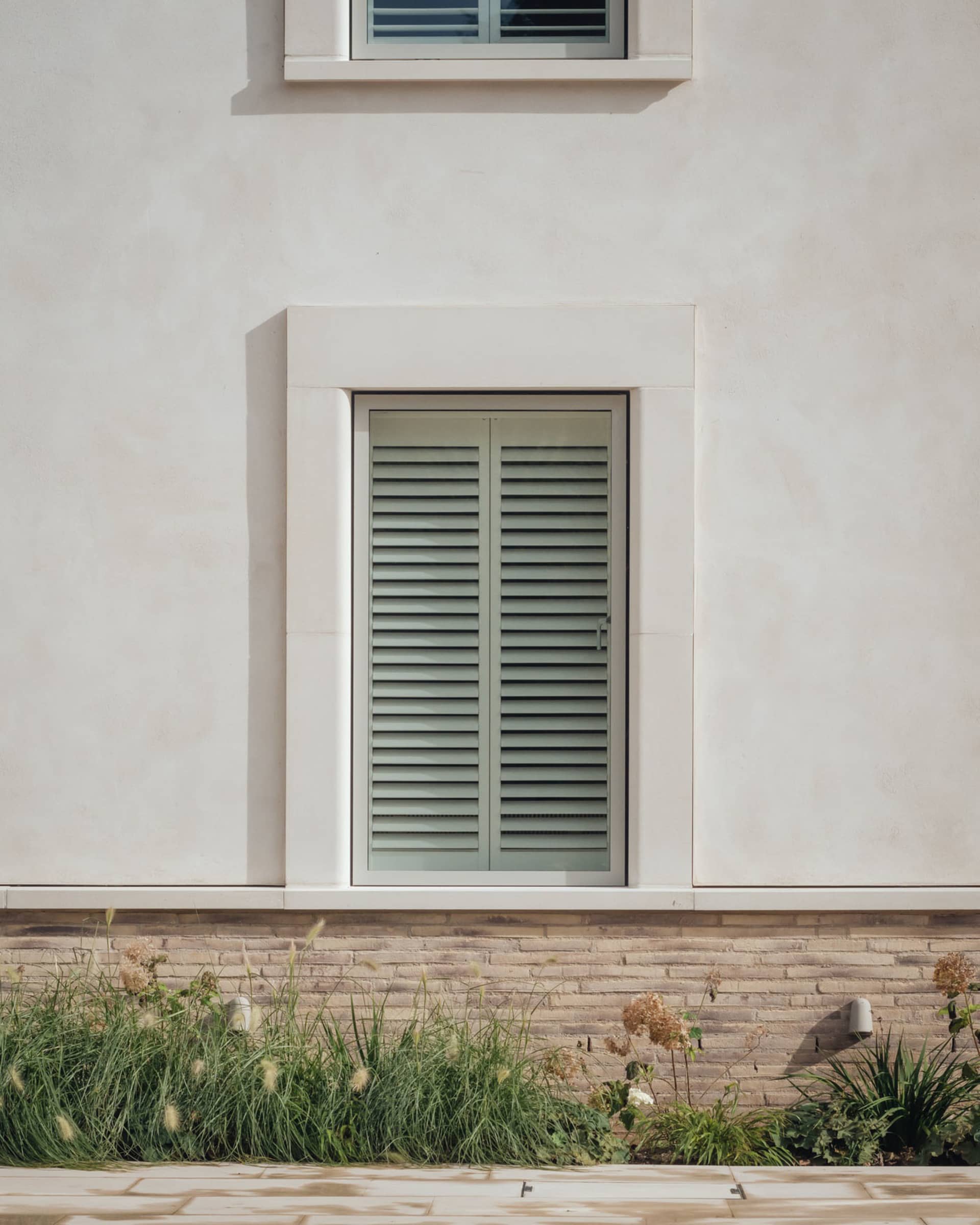 Window with white primative stucco and brick material